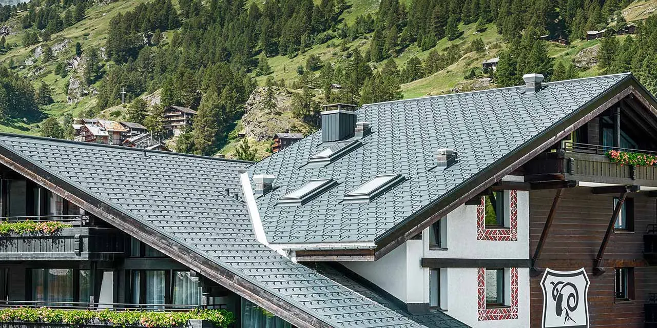 Hotel Alpenhof in Zermatt (Zwitserland) met de Matterhorn op de achtergrond, een gevel en balkons in donker hout en een antracietkleurig aluminiumdak van PREFA