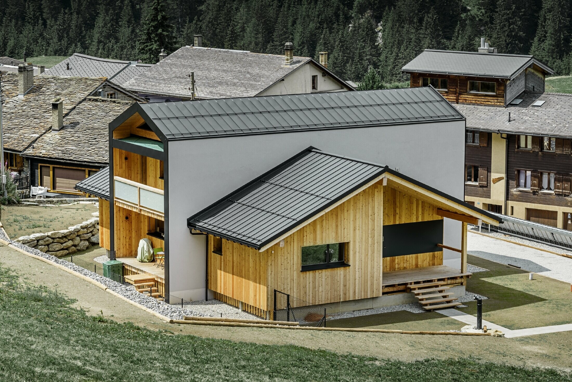 Cette maison individuelle donne l’impression que 2 maisons sont superposées selon un angle de 90°. Le toit est recouvert de Prefalz couleur noir et la façade est partiellement habillée de bois.