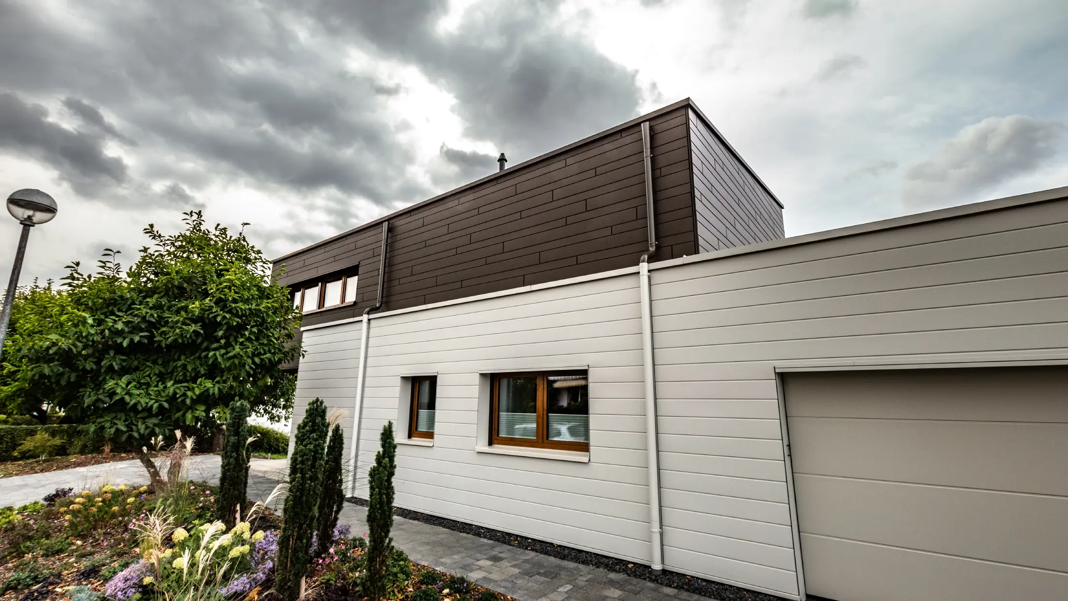 Fassadenverkleidung einer Garage mit den PREFA Sidings horizonal in Weiß, mit Speiereinmündung.