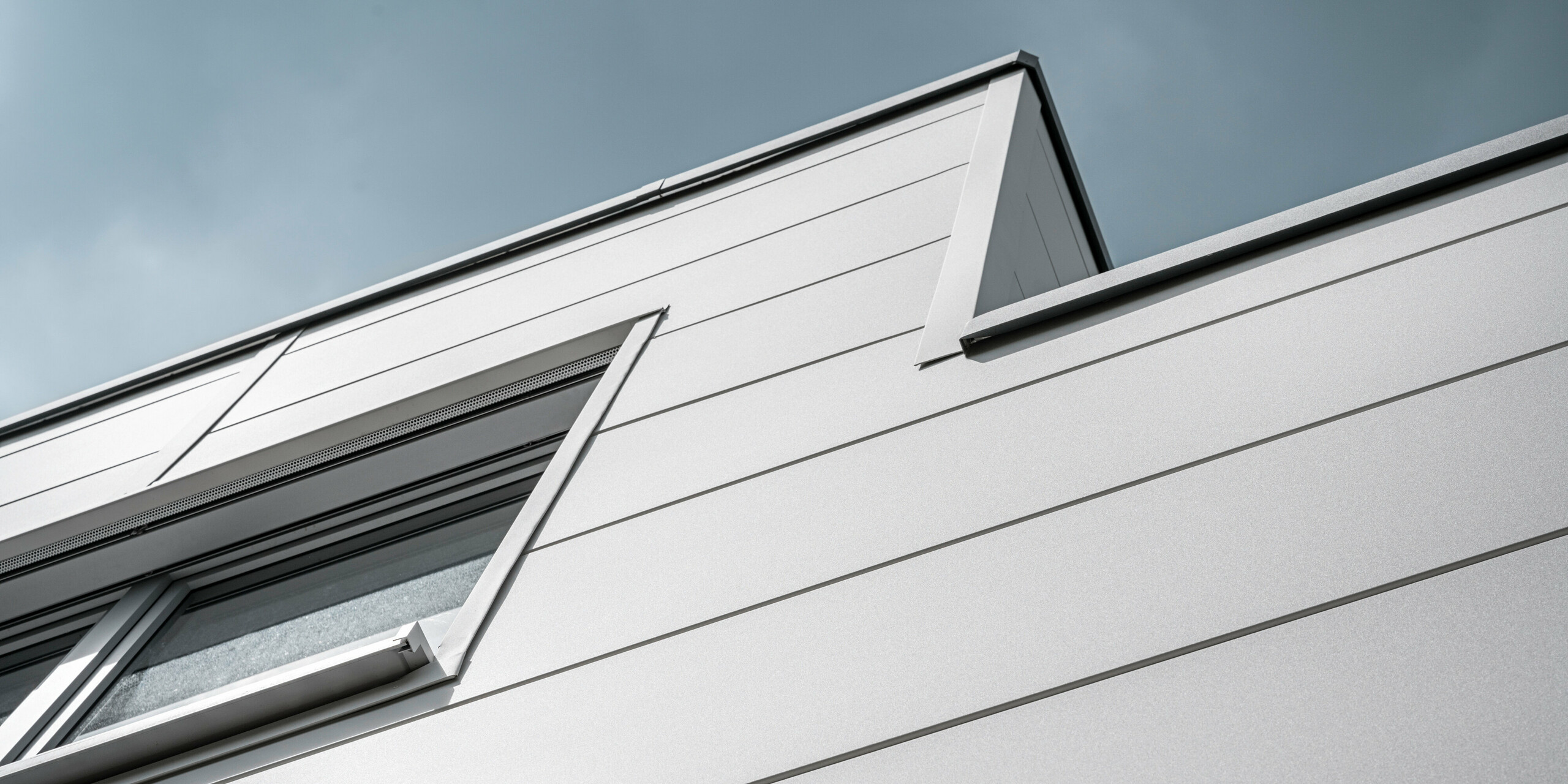 Des Sidings PREFA grand format entourent un bâtiment d'entreprise à Oberschleißheim (Allemagne). Les éléments de façade extra-larges en aluminium ont été choisis dans la couleur blanc Prefa.
