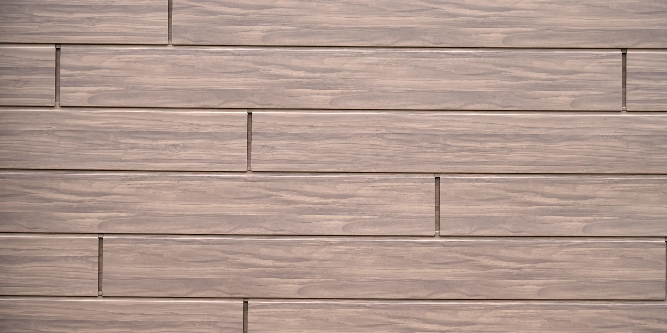 Detailaufnahme der PREFA Sidings in Walnussbraun mit authentischer Holzoptik am Firmengebäude der Dokter Schoonmaakorganisatie in Wolvega. Die elegante Maserung und das versetzte Fassadenbild schaffen eine moderne, hochwertige Optik. Die Aluminiumfassade vereint die warme Ausstrahlung von Holz mit langlebigen, korrosionsbeständigen, witterungsfesten und besonders pflegeleichten Eigenschaften.