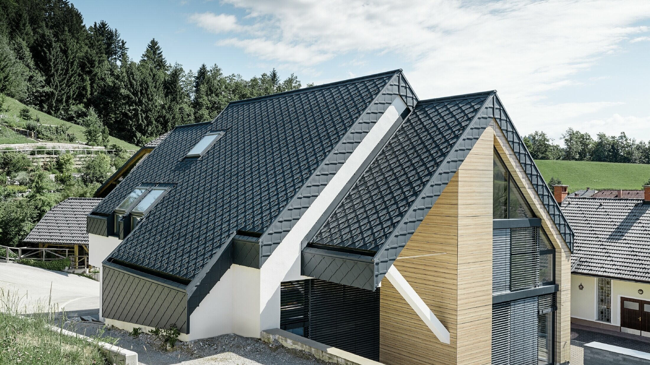 Maison individuelle avec toit à deux versants sans saillie, avec façade imitation bois et toit en aluminium couleur anthracite