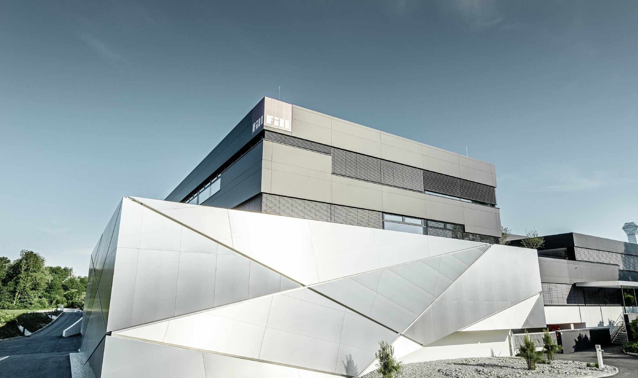 Bedrijfsgebouw (Fill) met futuristische gevel met composietplaten in geborsteld aluminium en achtergrondverlichting in de voegen.