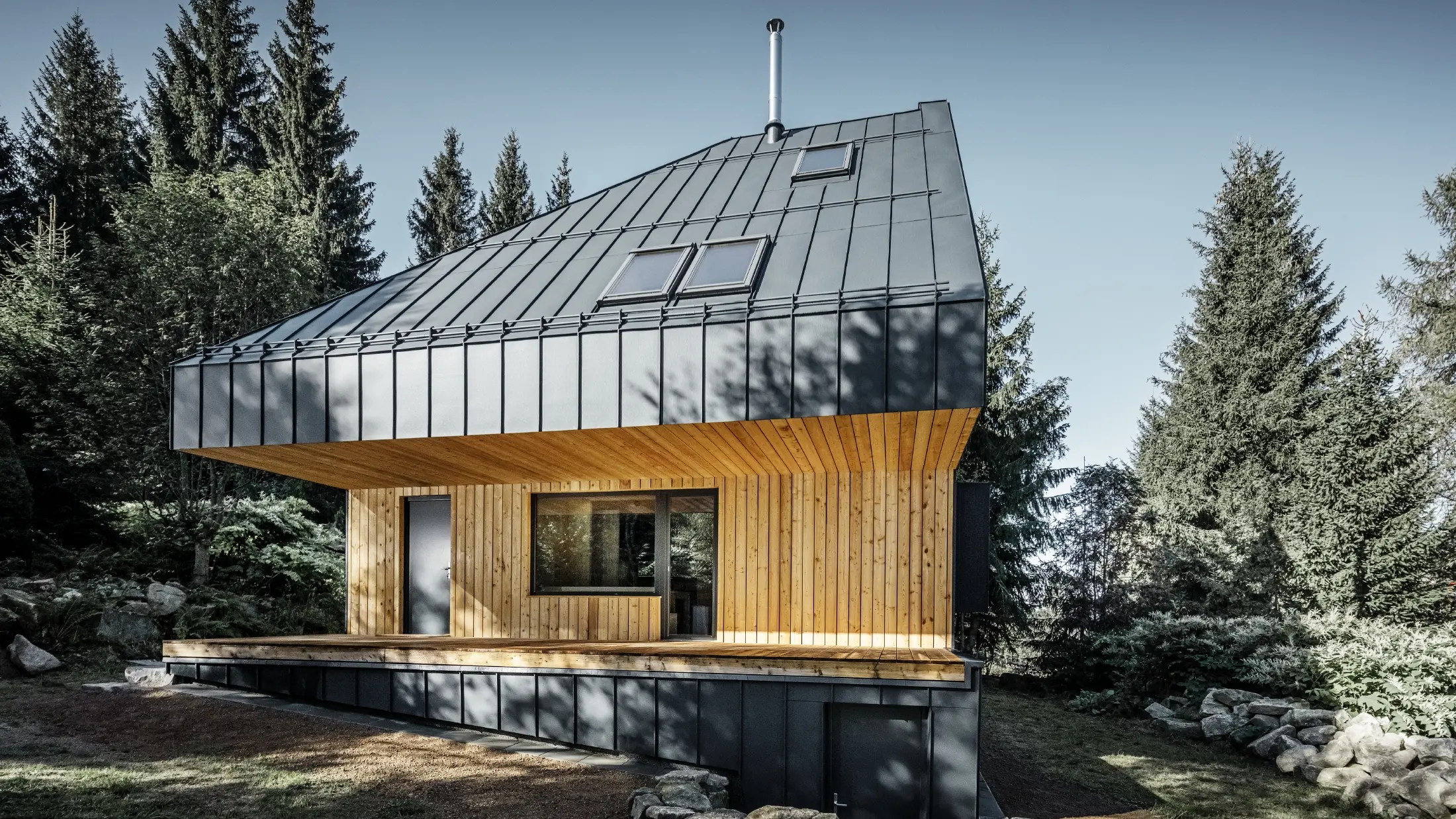Architectonisch vrijstaand huis in het bos, het imposante dak werd bekleed met PREFA Prefalz aluminium in antraciet. Het dakbeschot en de gevel zijn bekleed met houten panelen.