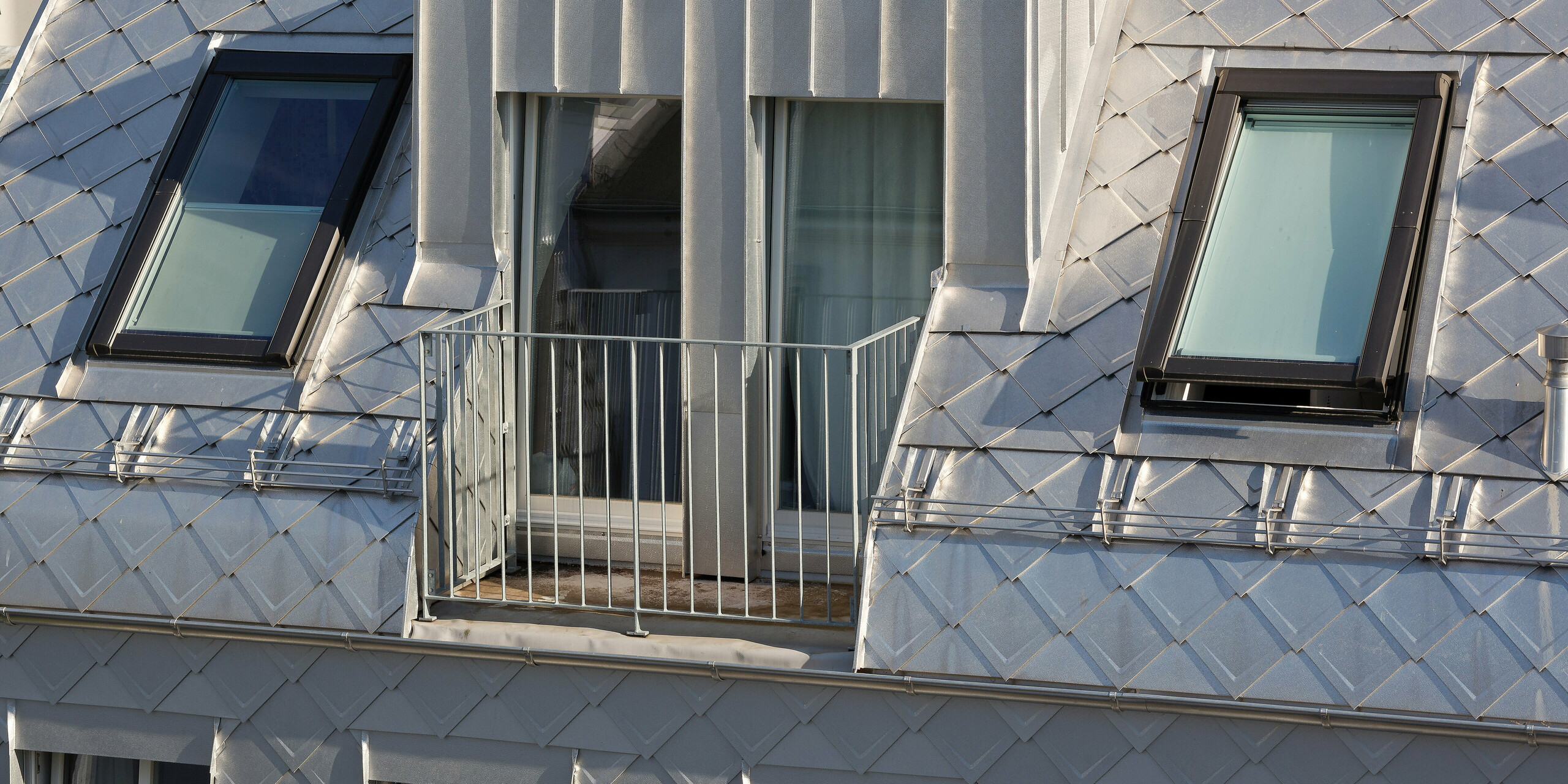 Das Dach dieses modernen Wohngebäudes in Hamburg wurde mit PREFA Dachrauten 29 × 29 in der Farbe Naturblank gedeckt. Dadurch erhält es eine auffällige, metallische Optik. Besonders hervorzuheben ist der charmante Balkon, der sich harmonisch in das Design des Daches einfügt.