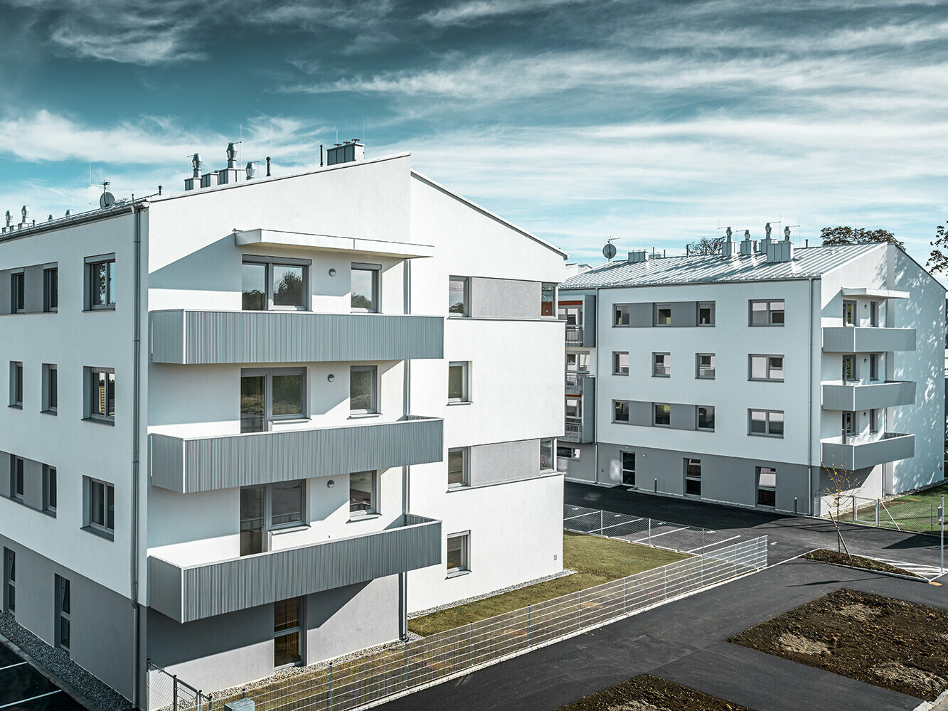 Modern woongebouw met witte gevel en balkons met PREFA kartelprofiel in zilvermetallic