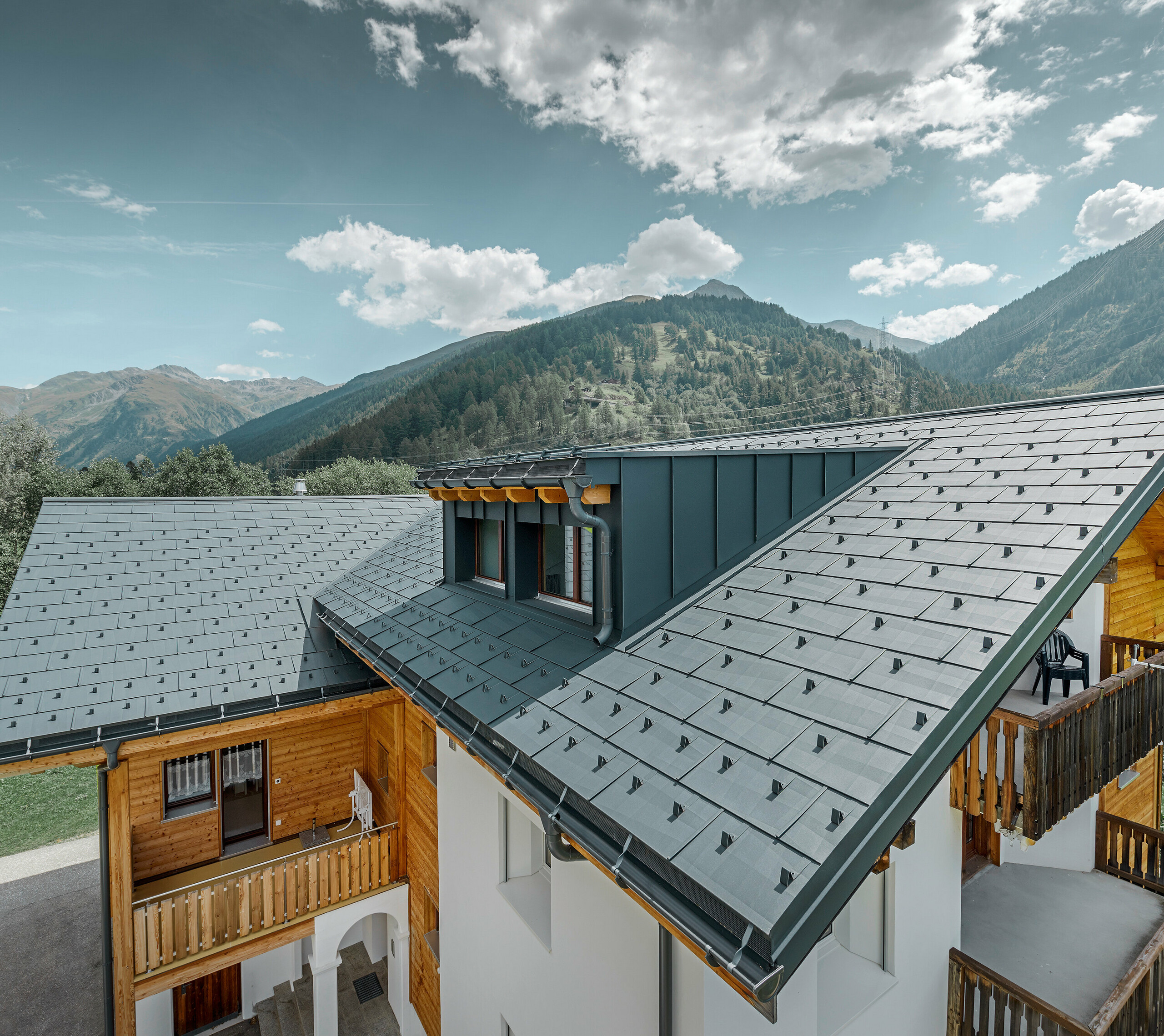 Bâtiment d’habitation rénové avec toit à deux pans et lucarne ; la rénovation de la toiture a été réalisée avec le panneau de toiture FX.12 PREFA couleur anthracite.