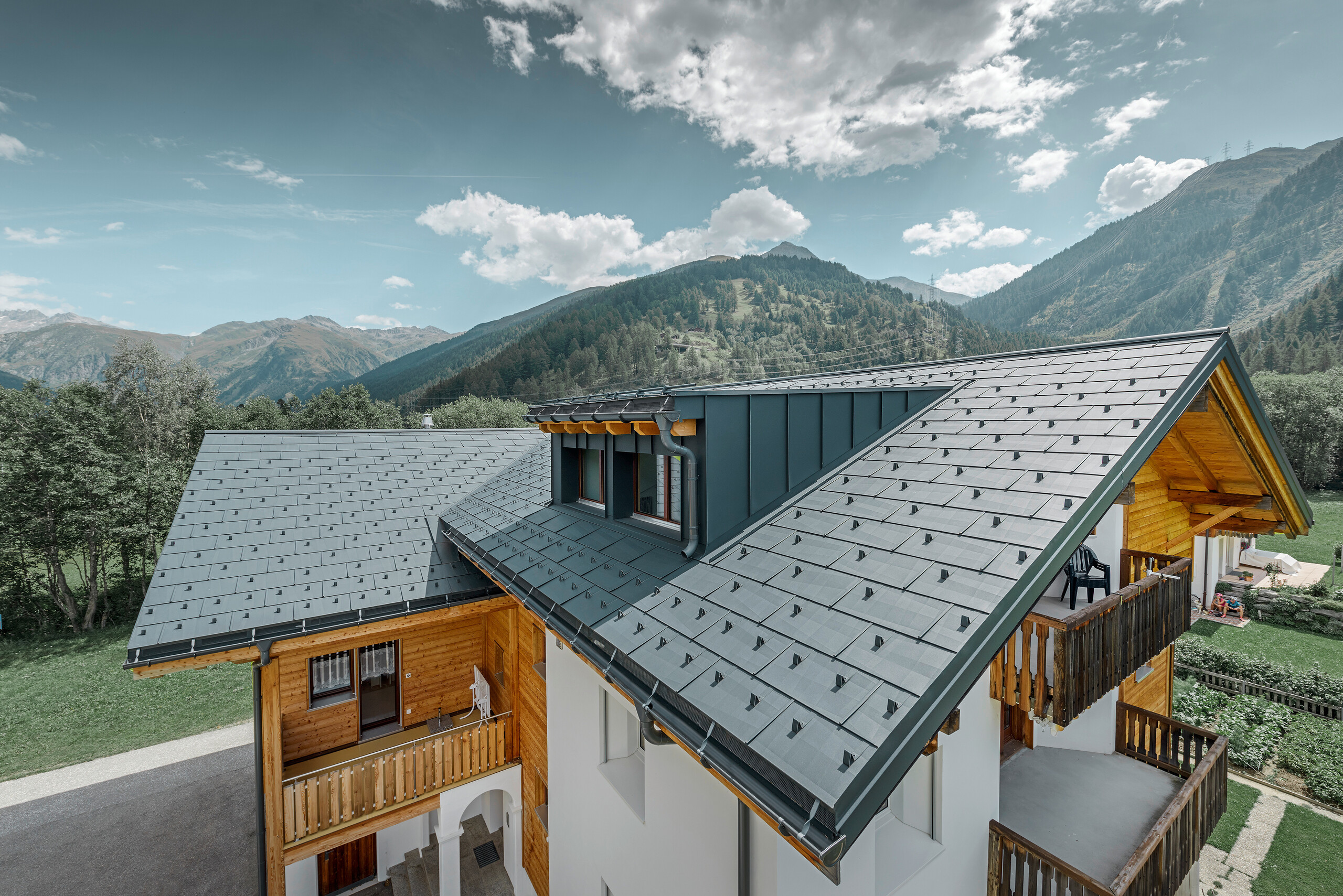 Bâtiment d’habitation rénové avec toit à deux pans et lucarne ; la rénovation de la toiture a été réalisée avec le panneau de toiture FX.12 PREFA couleur anthracite.