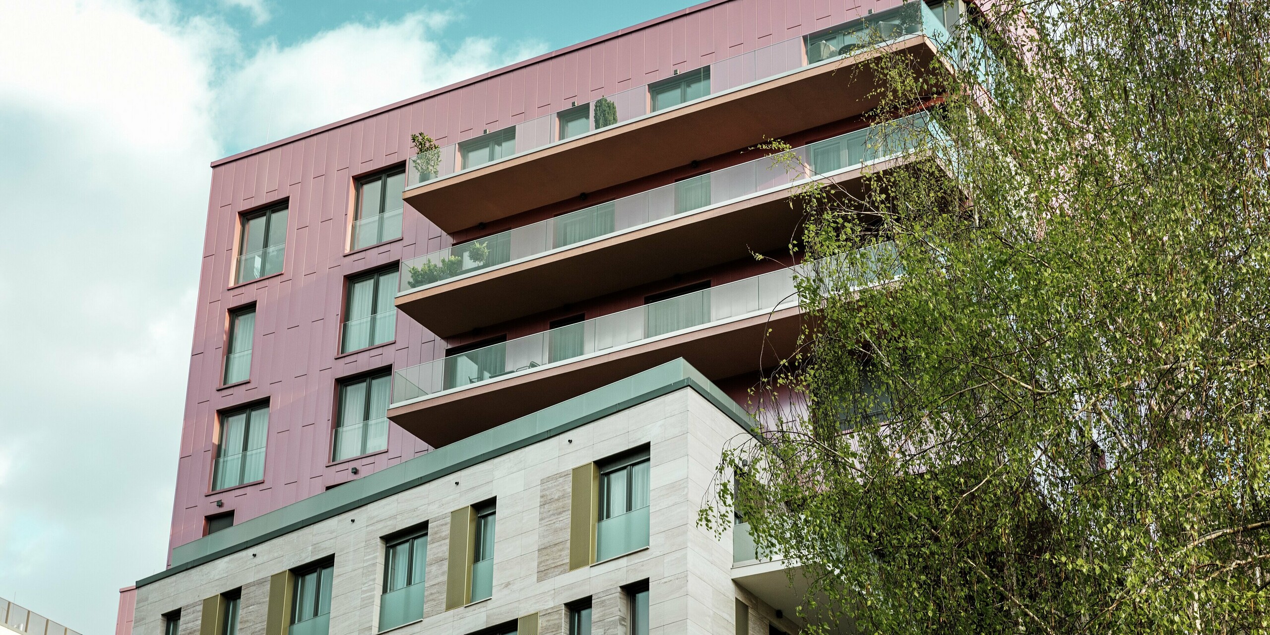 La partie supérieure du complexe résidentiel « Grand Corvin » à Budapest est dotée d'une remarquable façade en Siding PREFA en aluminium, posée verticalement et d'une couleur saumon métallisé brossé. Ces panneaux de façade de haute qualité confèrent au bâtiment une allure moderne et élégante et apportent une touche architecturale remarquable au quartier Corvin en pleine renaissance.