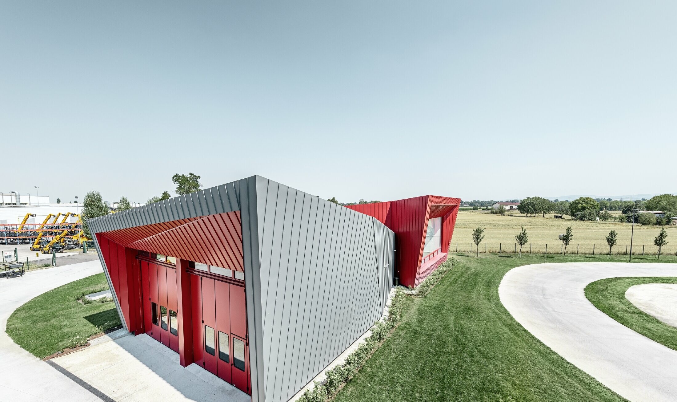 Modern opleidingscentrum van Dieci met tribune in Montecchio Emilia (Italië), bekleed met aluminium Prefalz-elementen in lichtgrijs en Falzonal-elementen in karmijnrood
