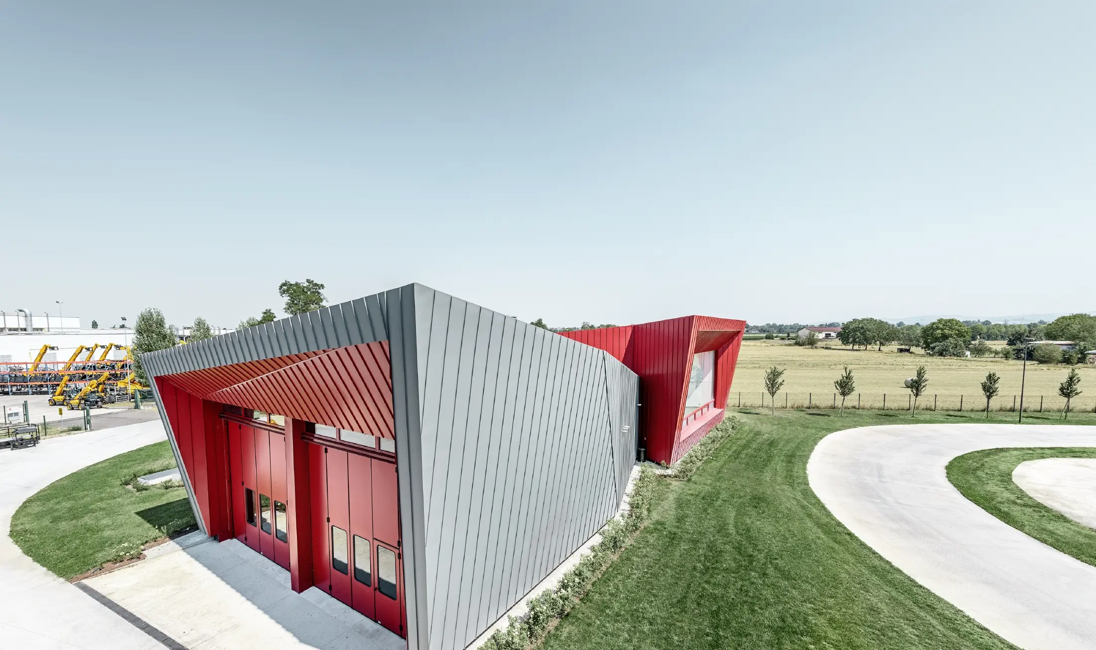 Centre d’entraînement moderne Dieci à Montecchio Emilia (Italie) — Façade des tribunes en aluminium réalisée avec des bandes Prefalz gris souris et Falzonal rouge carmin