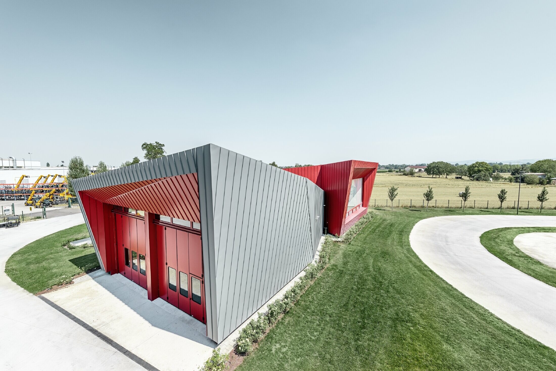 Centre d’entraînement moderne Dieci à Montecchio Emilia (Italie) — Façade des tribunes en aluminium réalisée avec des bandes Prefalz gris souris et Falzonal rouge carmin