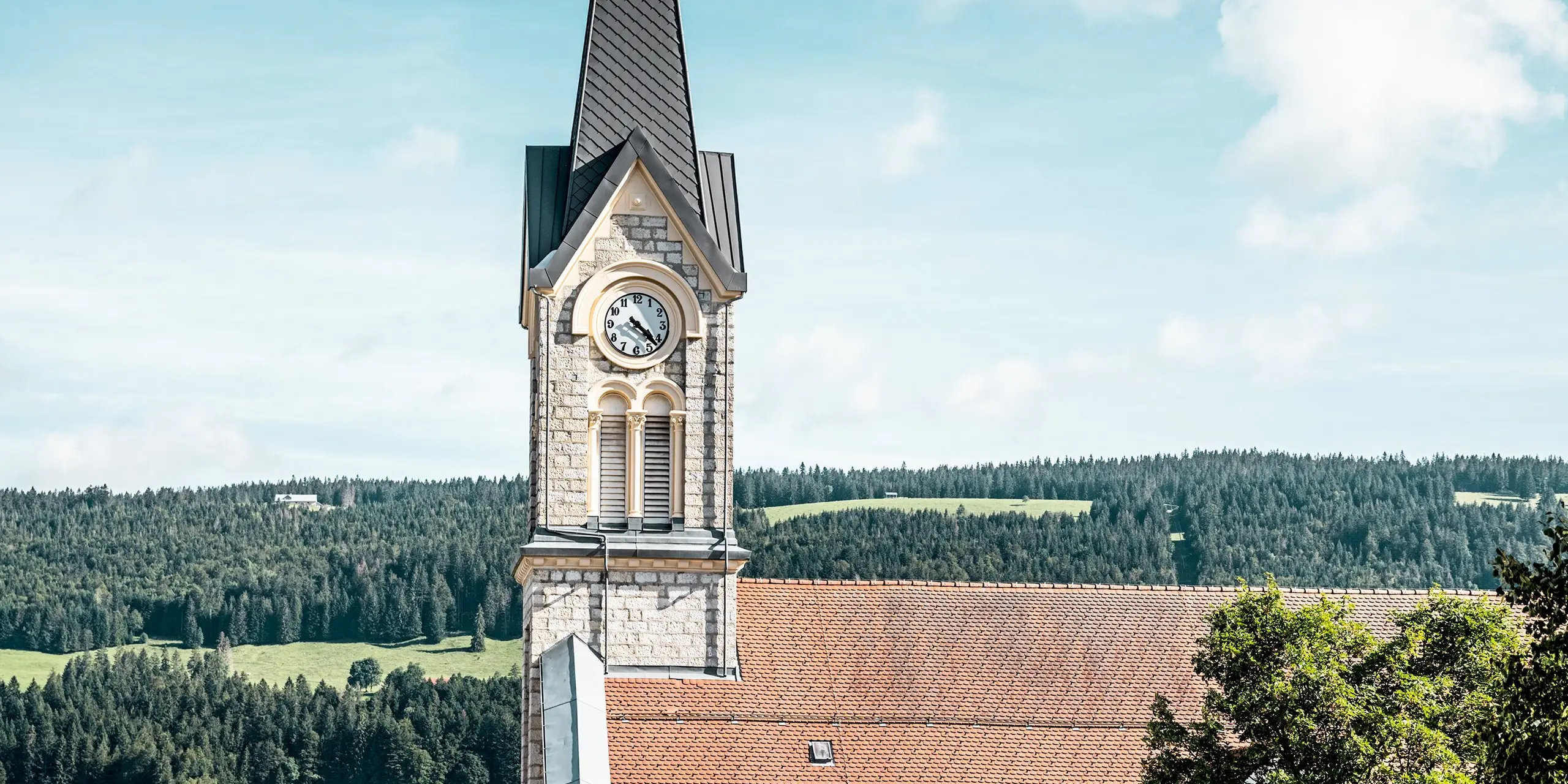 Die sanierte Kirche in Le Sentier fügt sich harmonisch in die weitläufige Schweizer Hügellandschaft ein. Blickfang ist die hoch aufragende Turmspitze mit PREFA Dachrauten 29 × 29 in P.10 Dunkelgrau, die dem historischen Bauwerk eine elegante und präzise Struktur verleihen. Die langlebige Aluminiumdeckung überzeugt durch hohe Witterungsbeständigkeit, geringes Gewicht und optimale Eignung für anspruchsvolle Turmgeometrien.