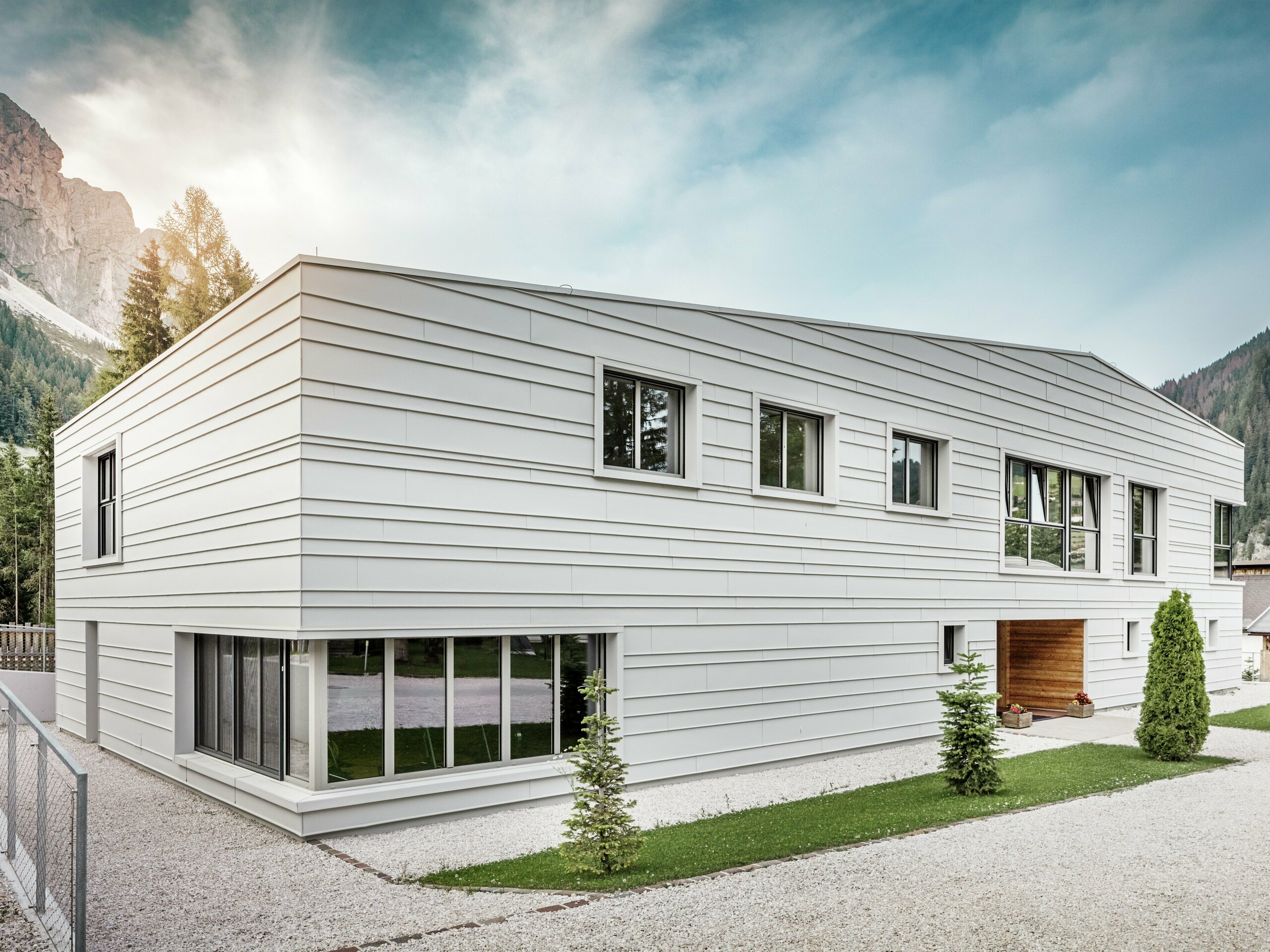 La façade moderne de la caserne « Tempesti » dans le Tyrol du Sud séduit par sa géométrie claire et ses panneaux à joints debout haut de gamme PREFALZ dans la couleur P.10 blanc Prefa. L'aluminium utilisé reflète la lumière, régule le microclimat et offre une protection durable. L'entrée revêtue de bois attire tous les regards et apporte chaleur et ouverture dans cet environnement militaire austère.