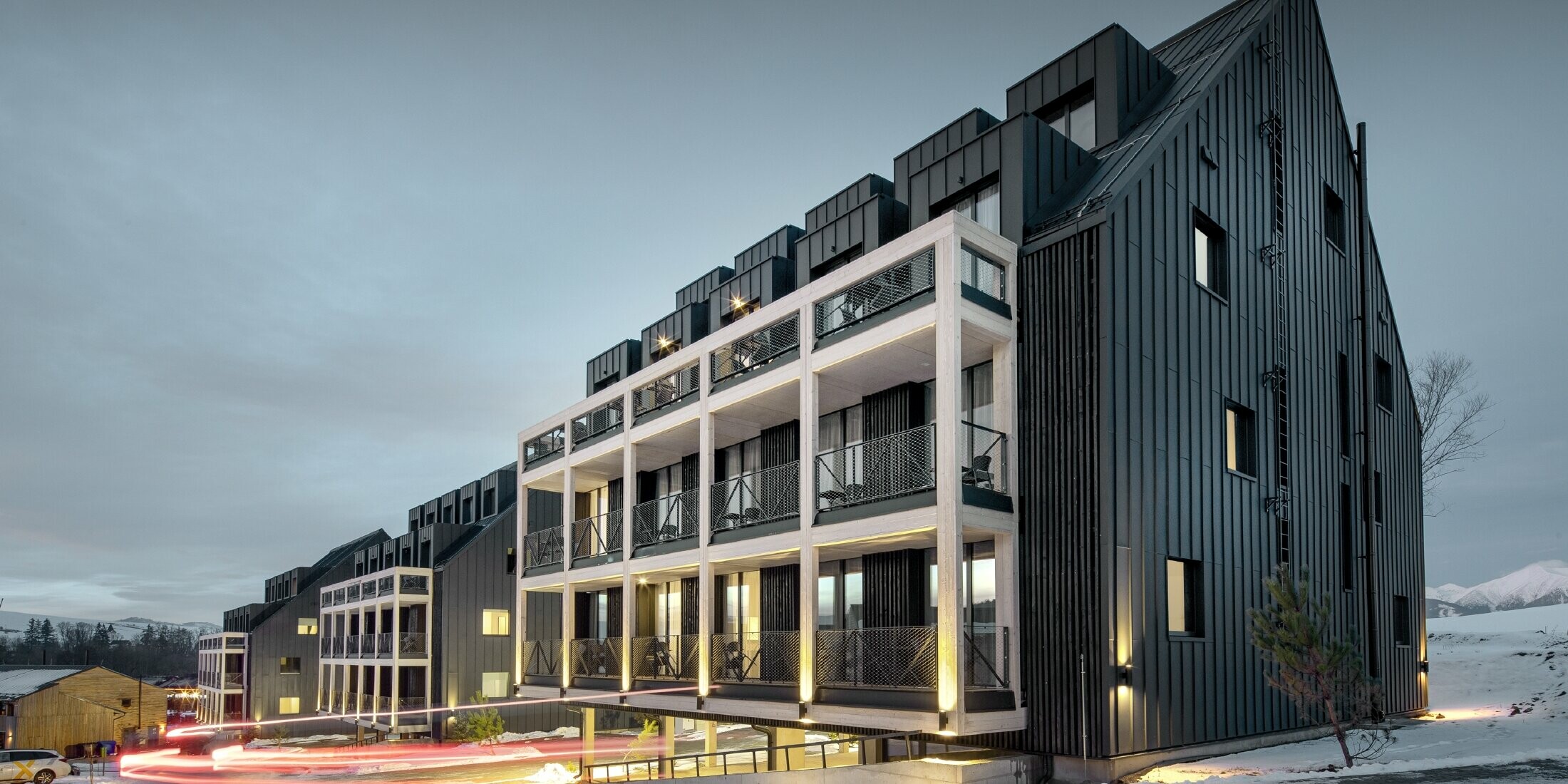 Bâtiments de station de ski en Slovaquie avec balcons et lucarnes, les façades sont habillées de Prefalz couleur anthracite, tout comme le toit à deux versants, environnement enneigé