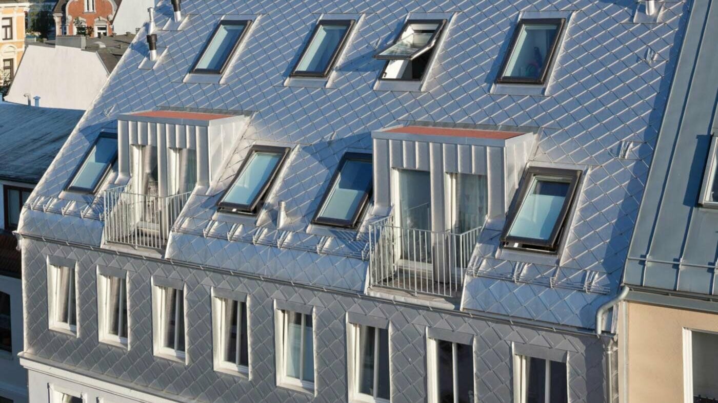 Blank aluminium dak met schubbenlook bij verbouwing dakverdieping met veel dakramen