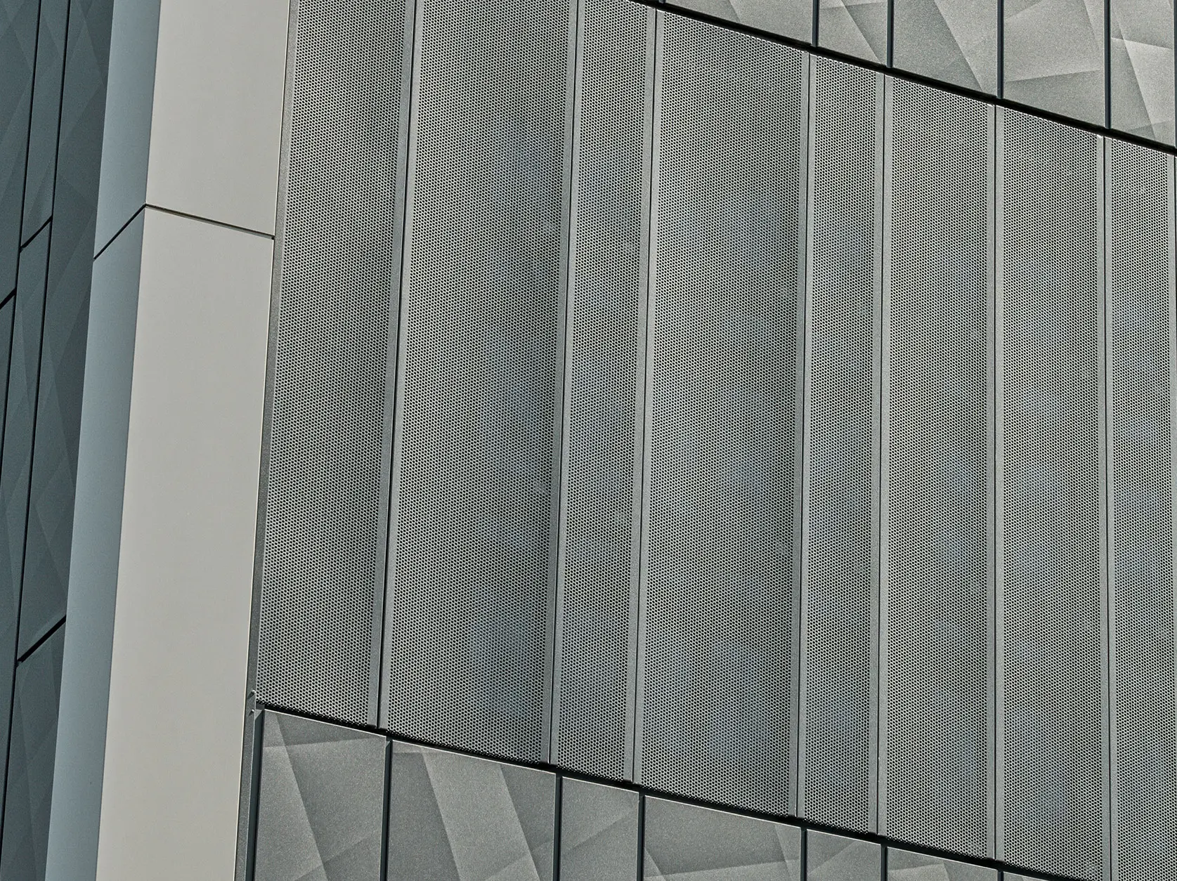 Vue de la façade d'un magasin Eurospar à Rohrbach avec des bardages PREFA Siding.X et des bardages perforés de couleur anthracite. Les éléments Siding.X présentent un motif de joints géométrique vivant, tandis que les bardages perforés offrent une structure moderne et perméable à l'air.