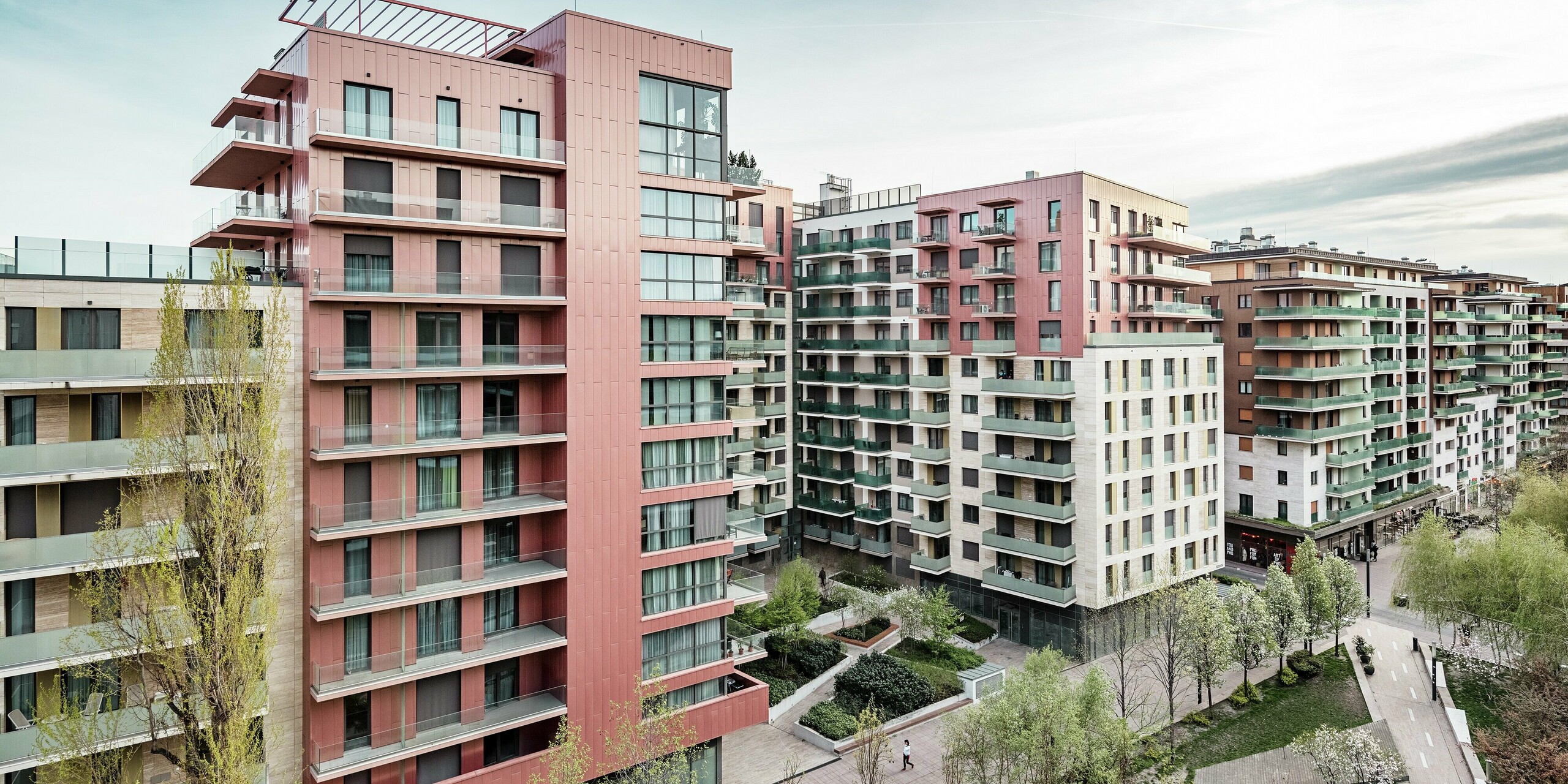 Vue panoramique du complexe résidentiel Grand Corvin, situé dans le nouveau quartier Corvin de Budapest. Les imposantes sections du bâtiment sont revêtues de plus de 800 m² de panneaux de façade Siding PREFA, posés verticalement et revêtus d'une finition saumon métallisée. Ce revêtement en aluminium durable crée des points forts architecturaux, s'intègre harmonieusement au tissu urbain et souligne le caractère contemporain et haut de gamme du nouveau complexe résidentiel situé le long de la promenade Corvin.