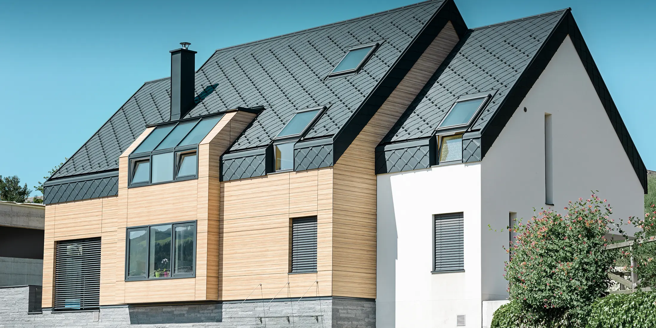 Nouvelle construction moderne avec un toit s’étendant jusqu’à la partie supérieure de la façade. Les losanges de toiture en aluminium couleur anthracite ont été utilisés pour la couverture