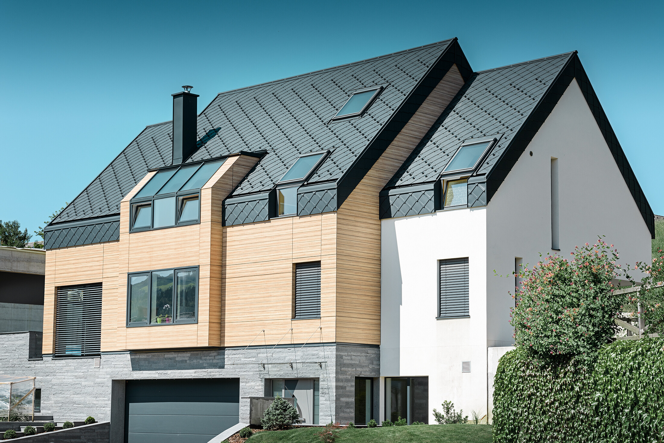 Nouvelle construction moderne avec un toit s’étendant jusqu’à la partie supérieure de la façade. Les losanges de toiture en aluminium couleur anthracite ont été utilisés pour la couverture