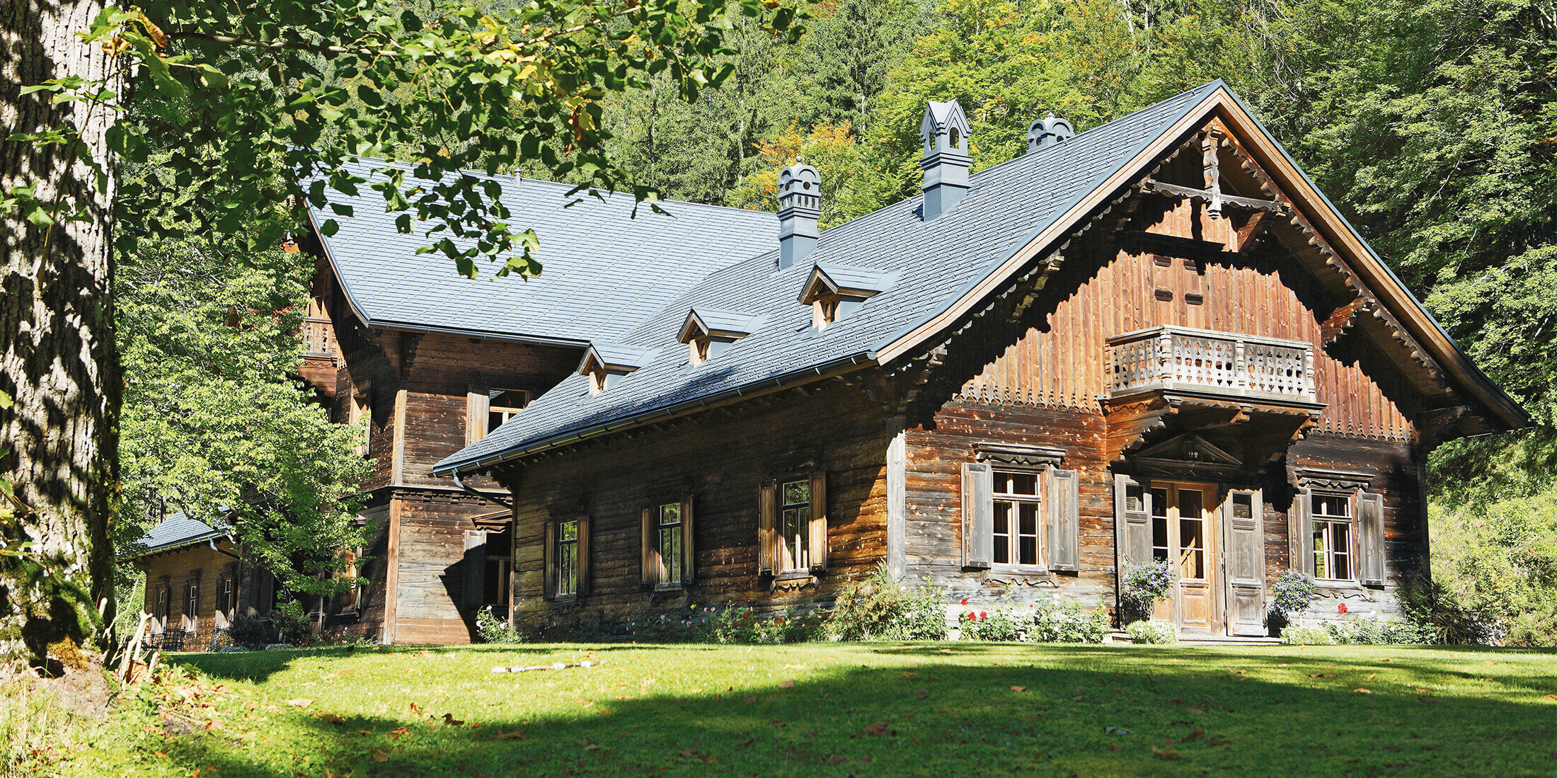 Rothschildhaus in Langau bei Gamin: Forst- und Jagdhütte mit hochwertigem Blechdach aus PREFA Dachschindeln in Anthrazit. Das Holzhaus fügt sich harmonisch in eine malerische Waldlandschaft ein.