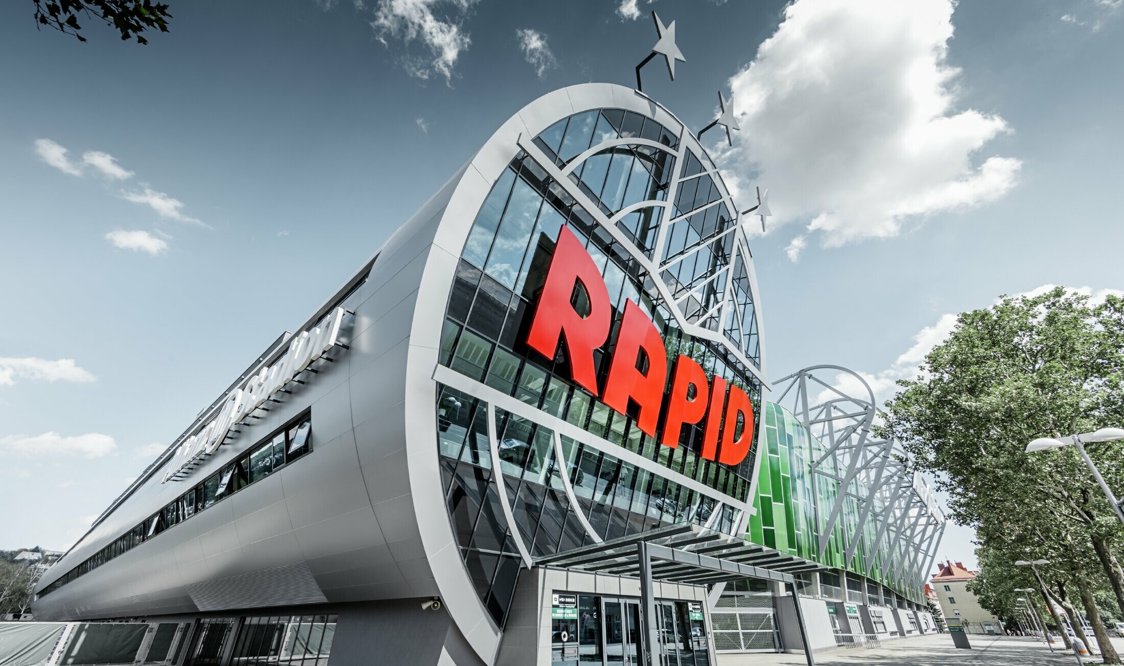 De ingang van het Allianz stadion met het grote SK Rapid Wien logo; de buis met de grote glazen front is afgewerkt met de PREFA aluminium composietplaat in zilvermetallic.
