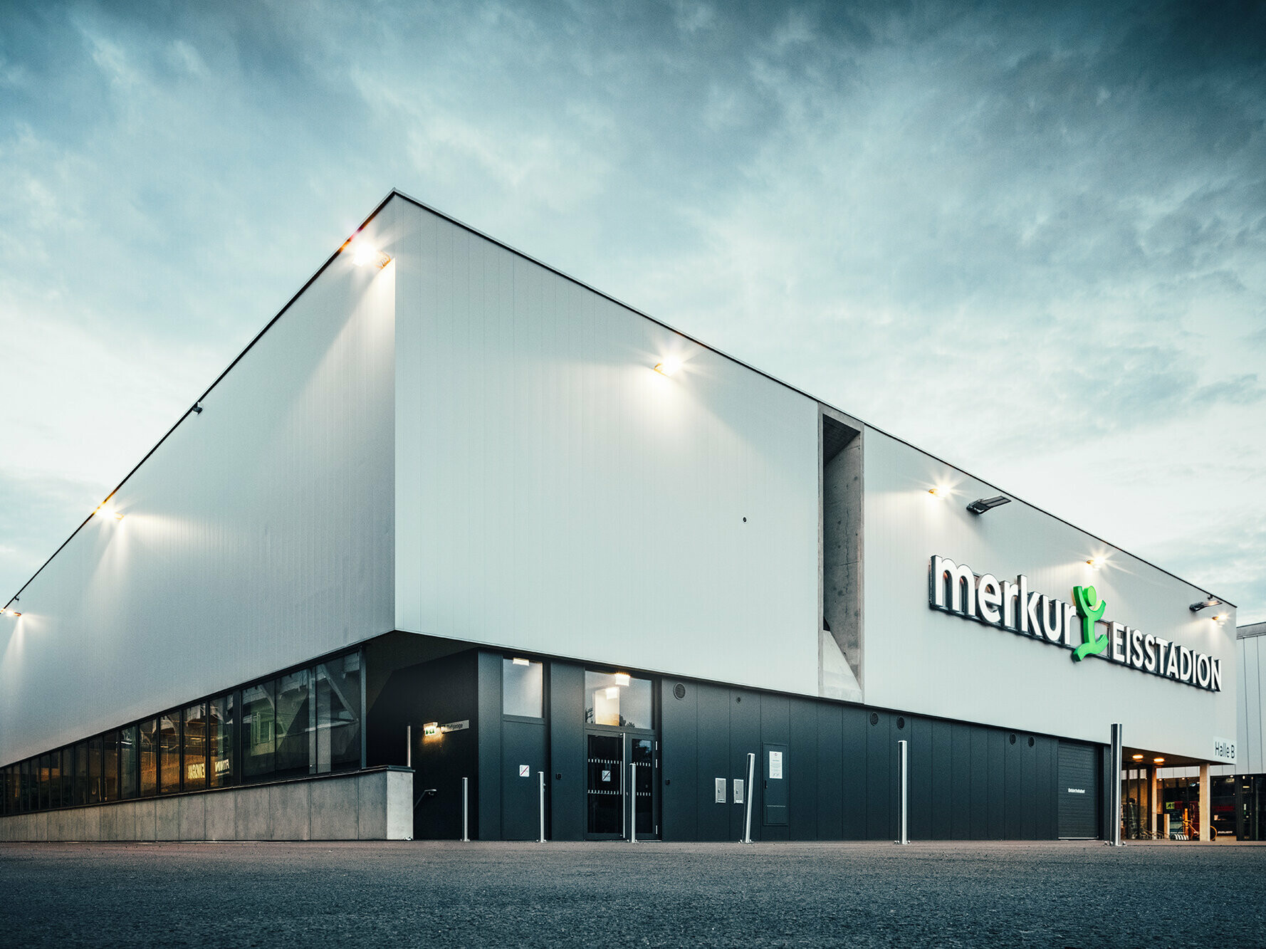 Eckaufnahme der Eishalle. An der rechten Seitenwand zu sehen: Lüftungsschacht und die Aufschrift "merkur EISSTADION" an der Fassade.