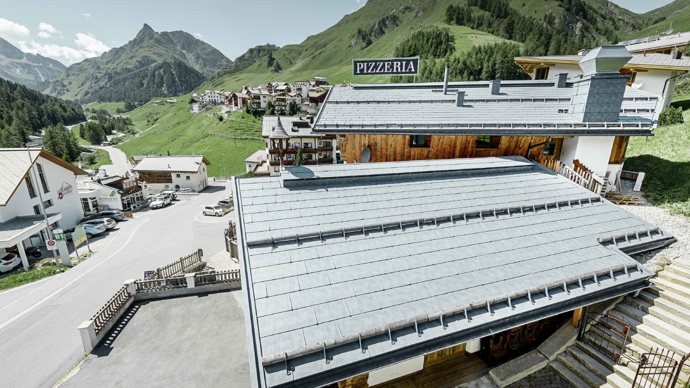 Restaurant Almrausch au cœur d’un décor de montagnes — Toiture PREFA réalisée avec des panneaux de toiture FX.12 gris pierre et dotée de tubes pare-neige