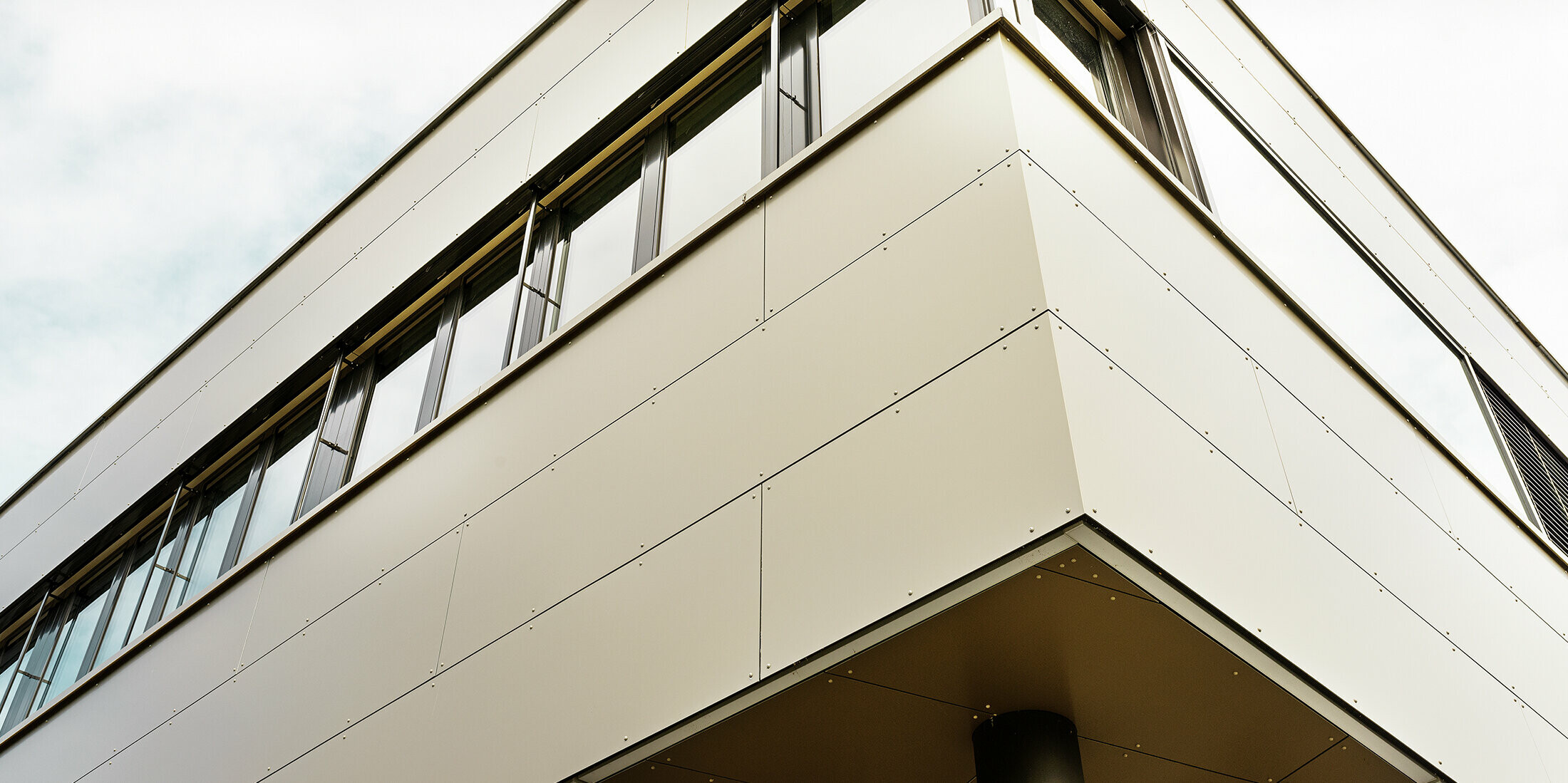 Moderne aanbouw met werkplaats en bureau afgewerkt met bronskleurige aluminium composietplaten van PREFA