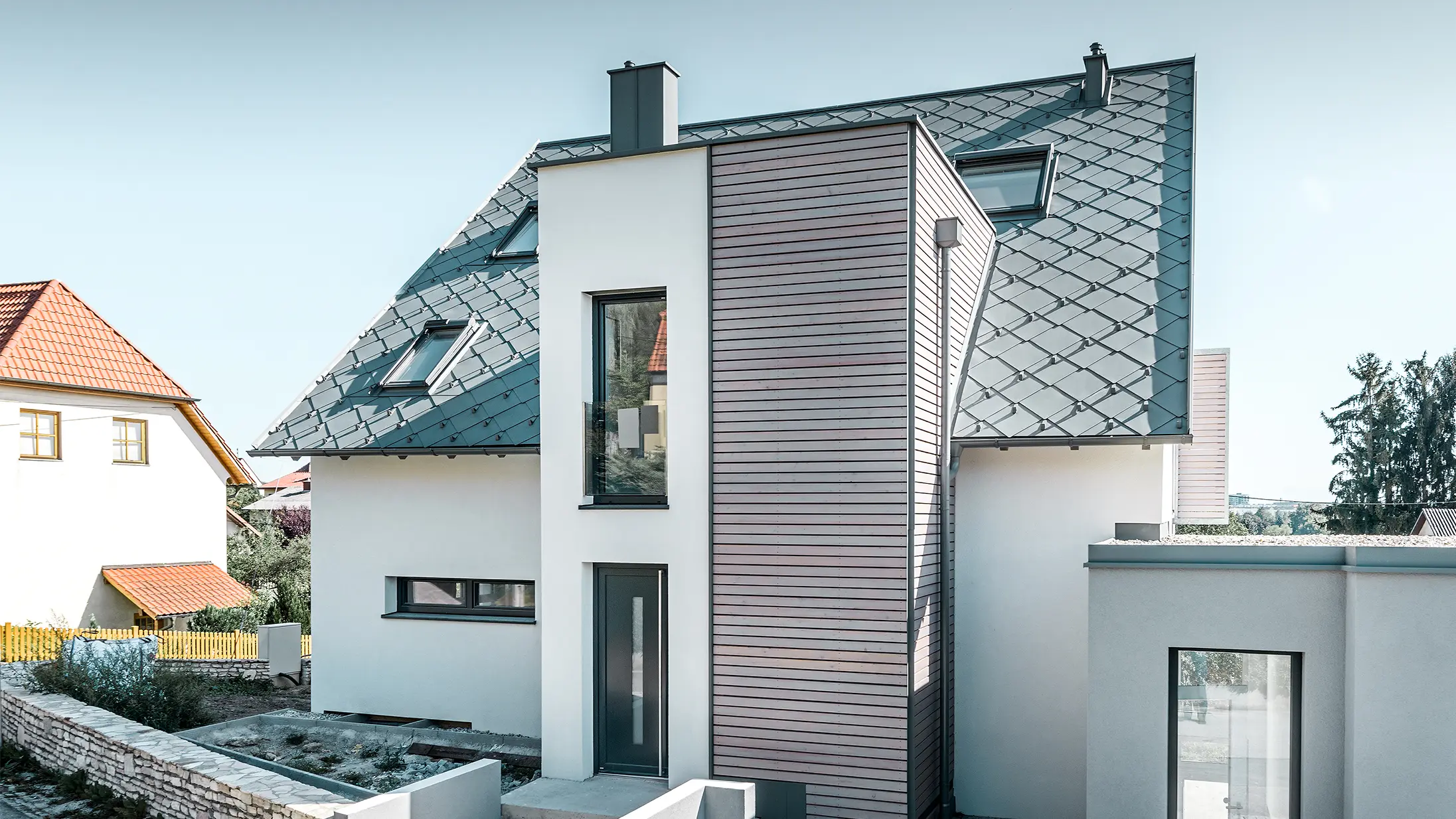 La maison individuelle avec toit à deux pans à Leonding a été entièrement rénovée. La surface de toit a été recouverte de losanges de toiture 44 × 44 PREFA couleur gris souris avec arrêts neige. Le choix s’est porté sur la gouttière suspendue de PREFA, également couleur gris souris. 