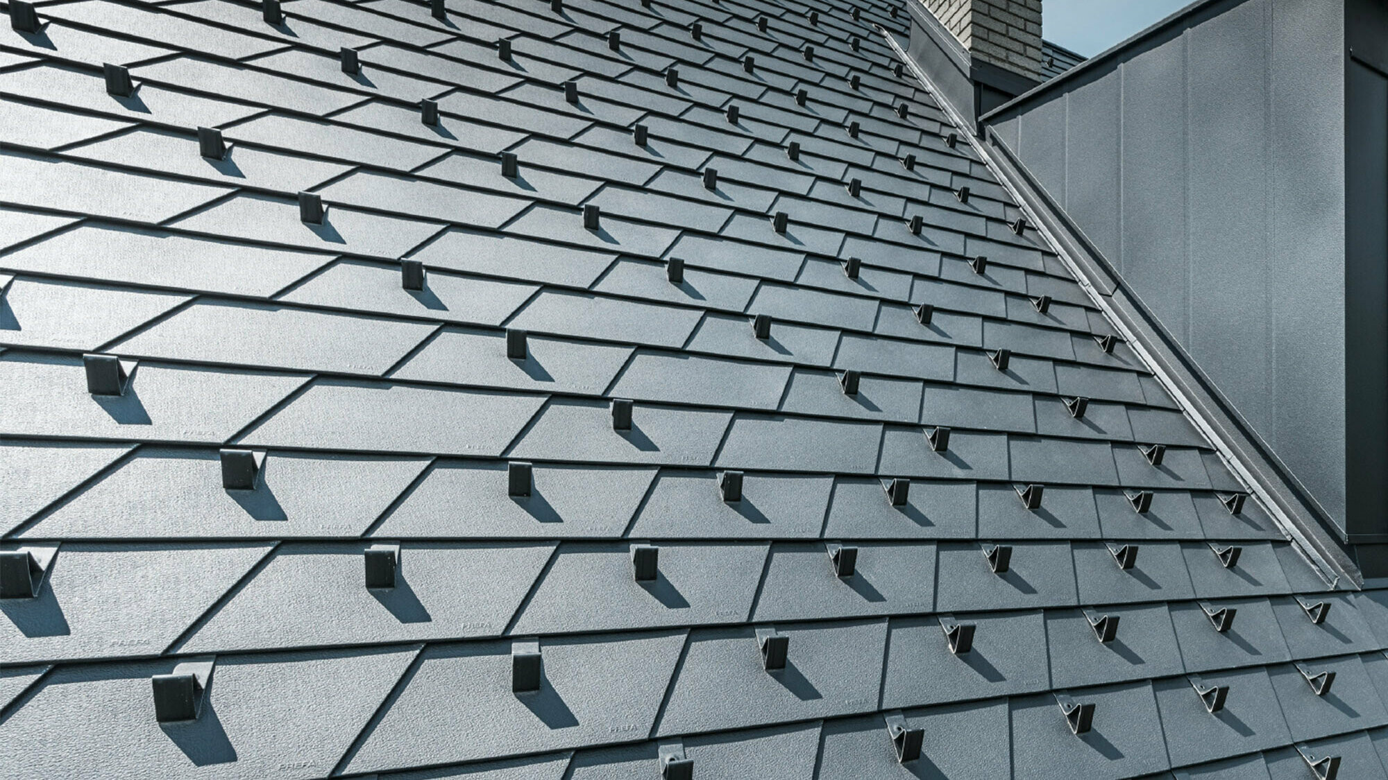 Toit rénové à l'aide de bardeaux de toiture PREFA dans la couleur P.10 noir avec arrêts de neige, lucarne revêtue d'aluminium PREFA