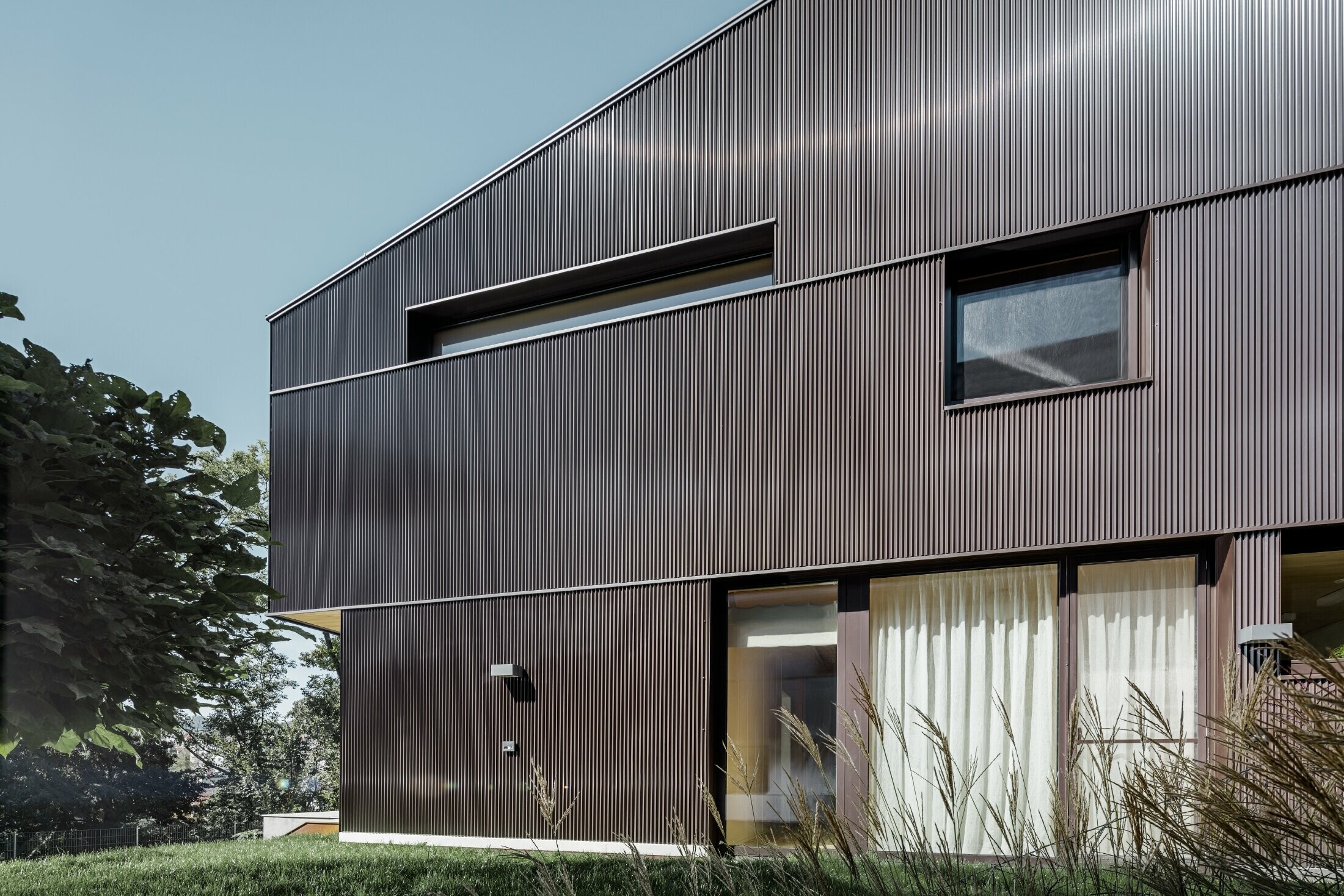 Maison individuelle moderne avec un habillage de façade en profil triangle PREFA couleur brun.
