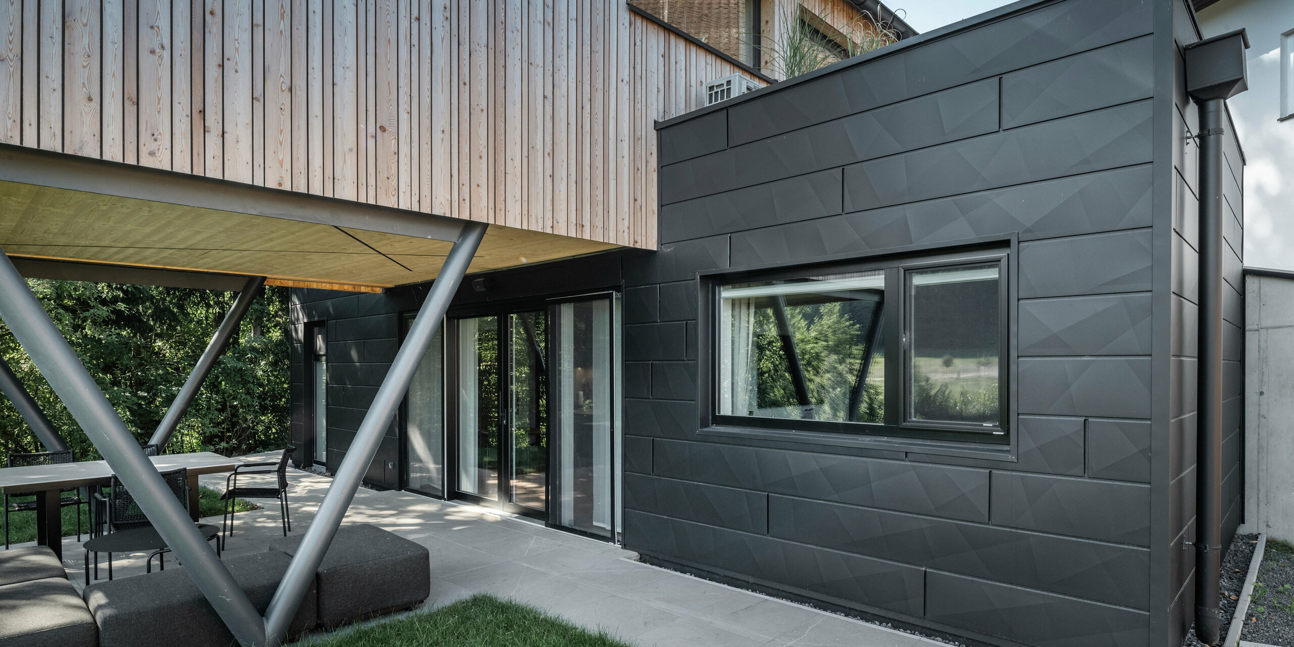 Detailaufnahme auf Chalet 5 mit Holzfassade und PREFA Aluminiumfassade aus Siding.X in P.10 Anthrazit