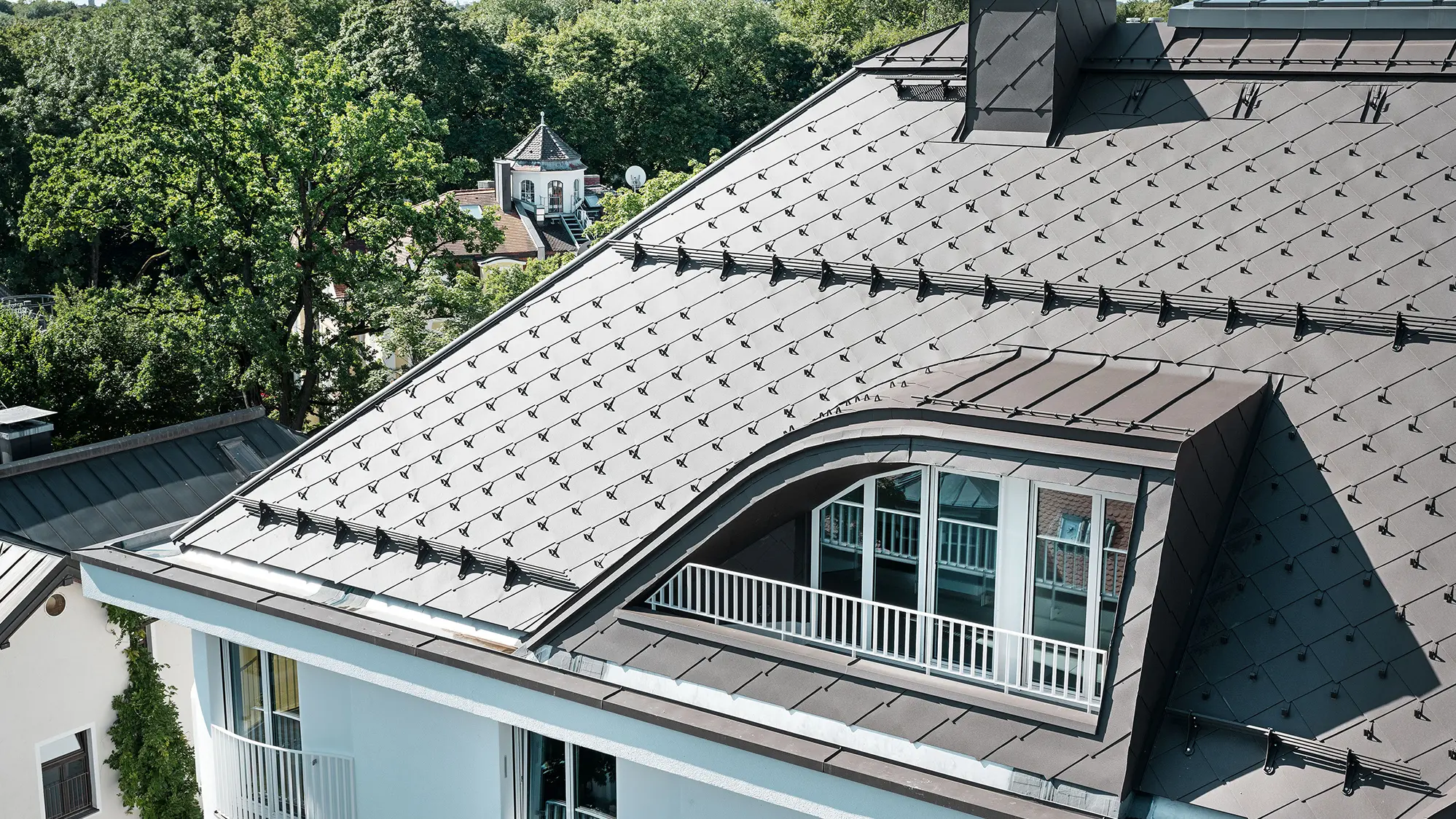 Immeuble résidentiel avec losange de toiture 44 × 44 de PREFA en brun avec arrêts neige et système pare-neige