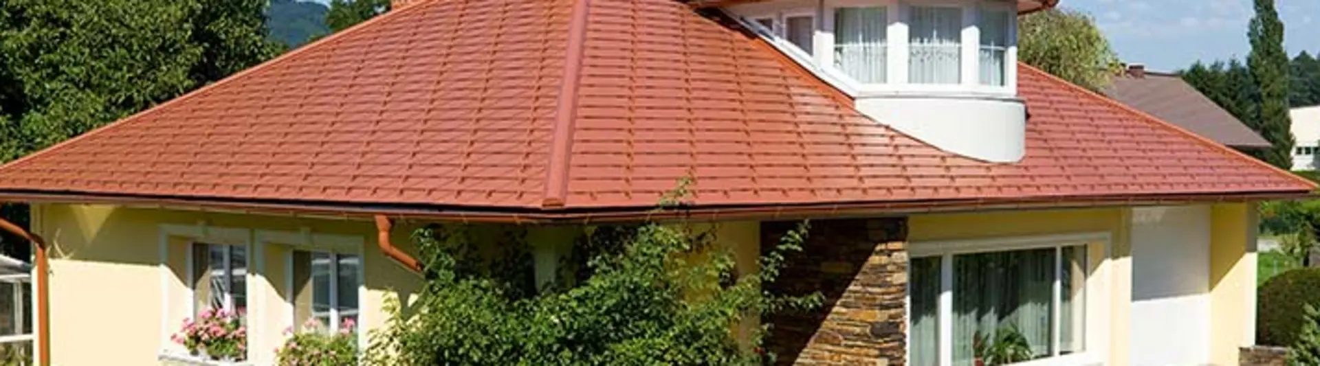 Eengezinswoning met schilddak en dakkapel bedekt met de aluminium PREFA-dakschindel in dakpanlook, baksteenrood.