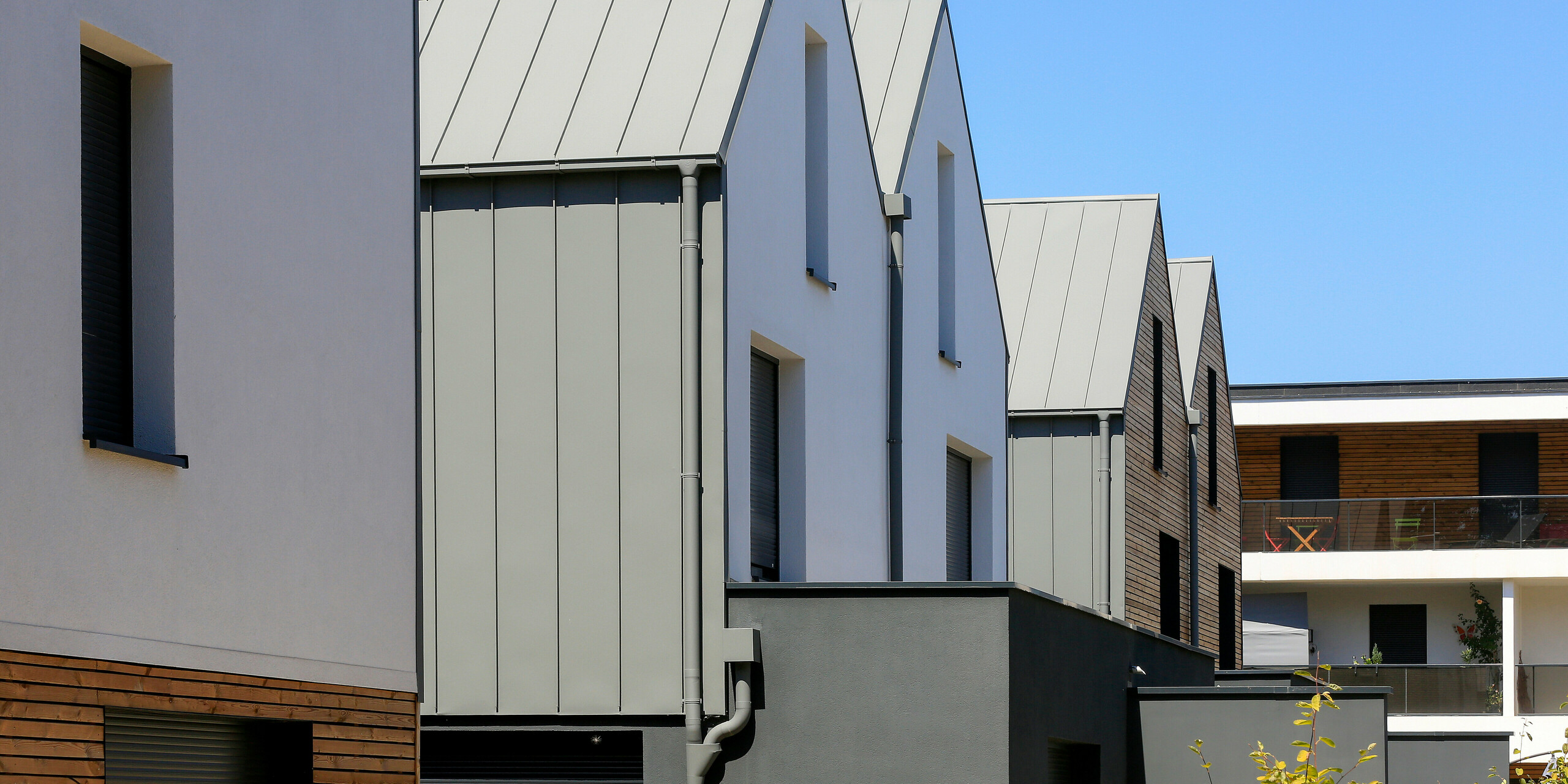 Le joint debout PREFALZ en gris souris s'étend sur les façades et les toits à pignon d'un lotissement mitoyen à Mundolsheim. Les coques uniformes du bâtiment en aluminium créent une image globale harmonieuse.