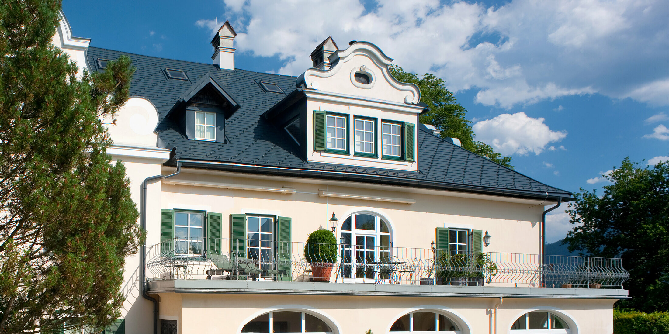 Eine dreistöckige Villa in Bad Aussee, Österreich, mit einem PREFA Dachsystem aus Aluminium. Für die große Dachfläche mit Gauben wurde die vielseitige PREFA Dachschindel in der Farbe P.10 Anthrazit gewählt.