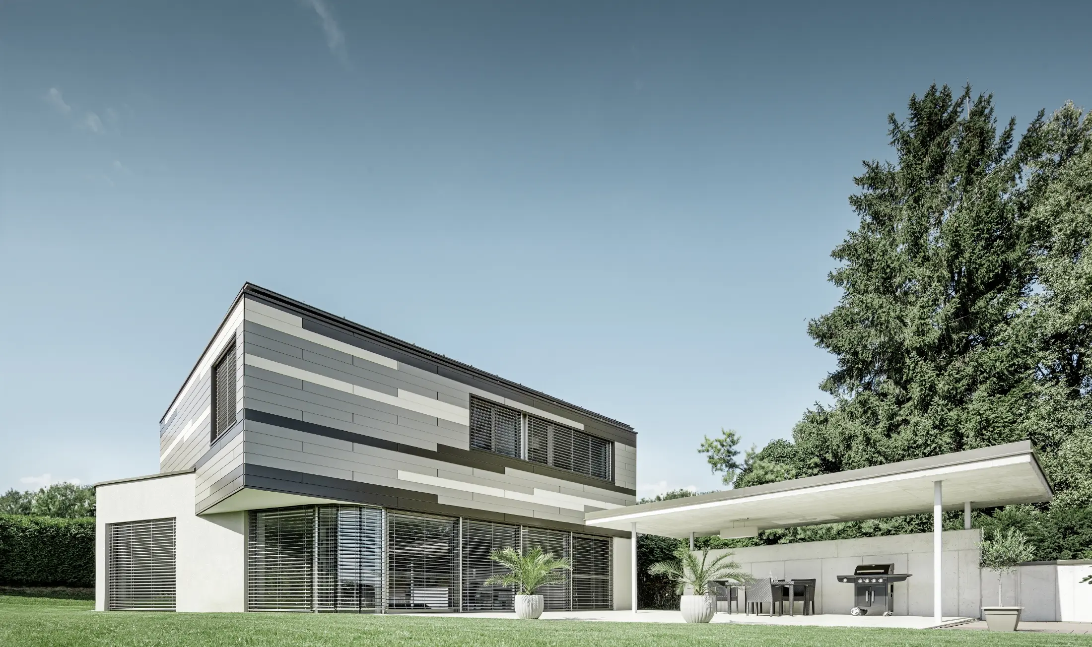 Eigentijdse gezinswoning met plat dak, overdekt terras en originele aluminiumgevel met PREFA-sidings in bruin, brons en ivoor