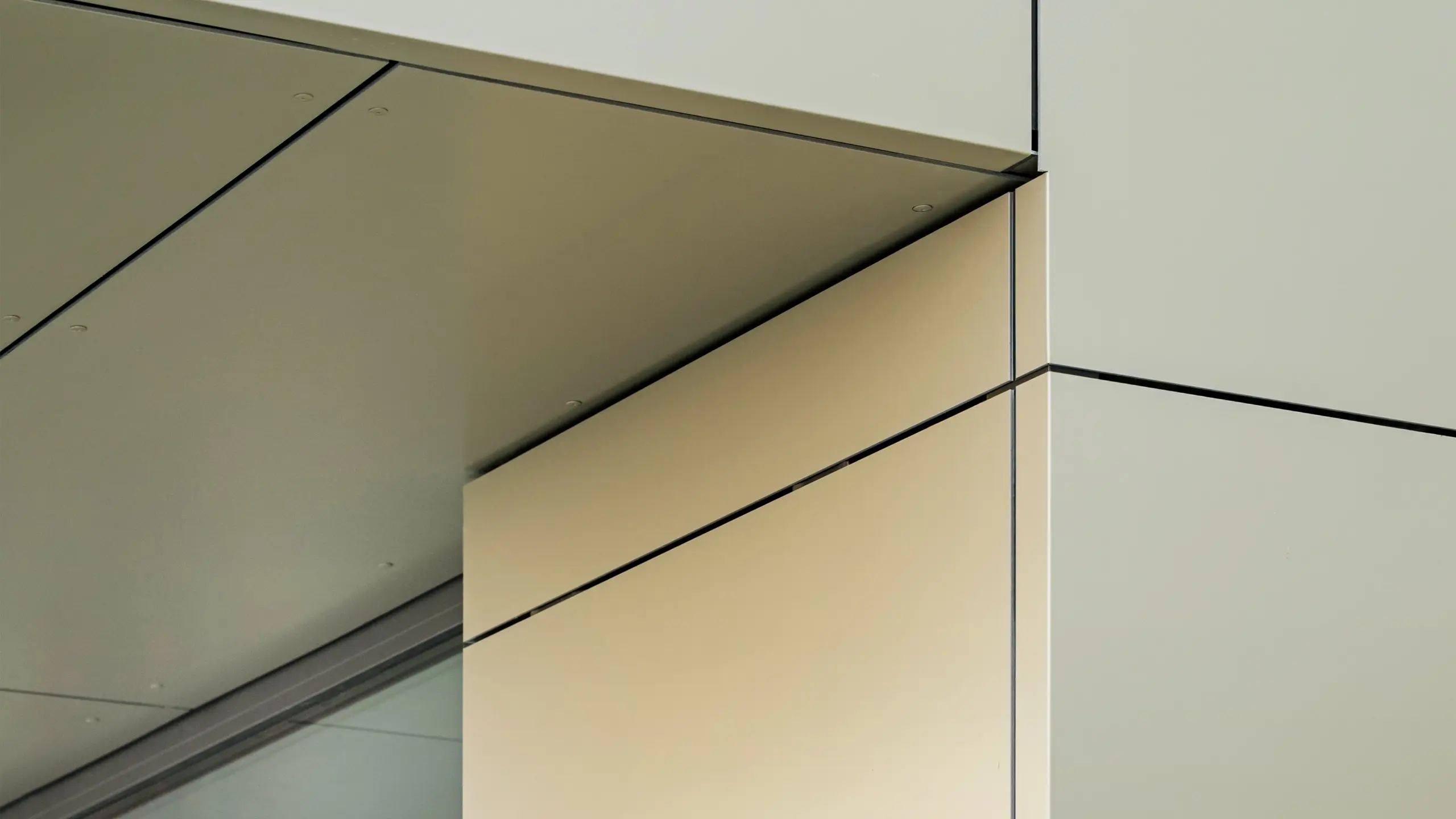 Detailaufnahme der Fassade des Rathauses in Alzenau, die die präzise Kante und Übergänge der Aluminium-Verbundplatten von PREFA hier in der Farbe bronze zeigt. Die Platten sind perfekt aneinandergefügt, wodurch eine klare, moderne Linienführung entsteht. Der metallische Glanz der Platten wird durch die feinen Fugenlinien und die minimalistischen Details der Architektur betont, was der Fassade ein elegantes und zeitgemäßes Aussehen verleiht.