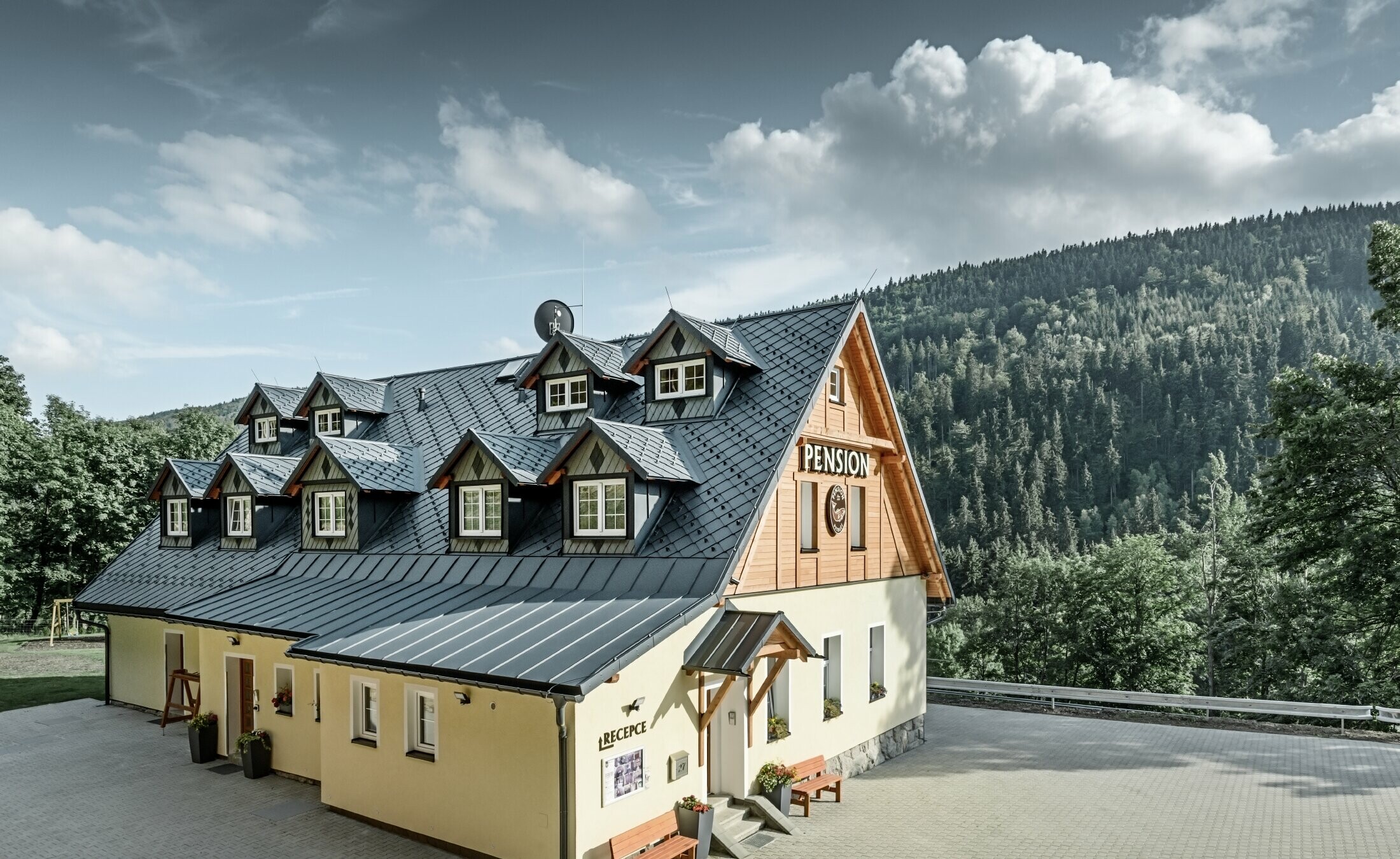 Pension in Tsjechië met schuin dak en veel dakkapellen bekleed met aluminium dakbedekking van PREFA, losangedak met schubbenlook met sneeuwbescherming