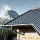 Tuile PREFA employée en région montagneuse - cabane recouverte avec des tuiles anthracite à Lech am Arlberg avec montagnes en arrière-plan ; gouttière PREFA anthracite ; façade en bois