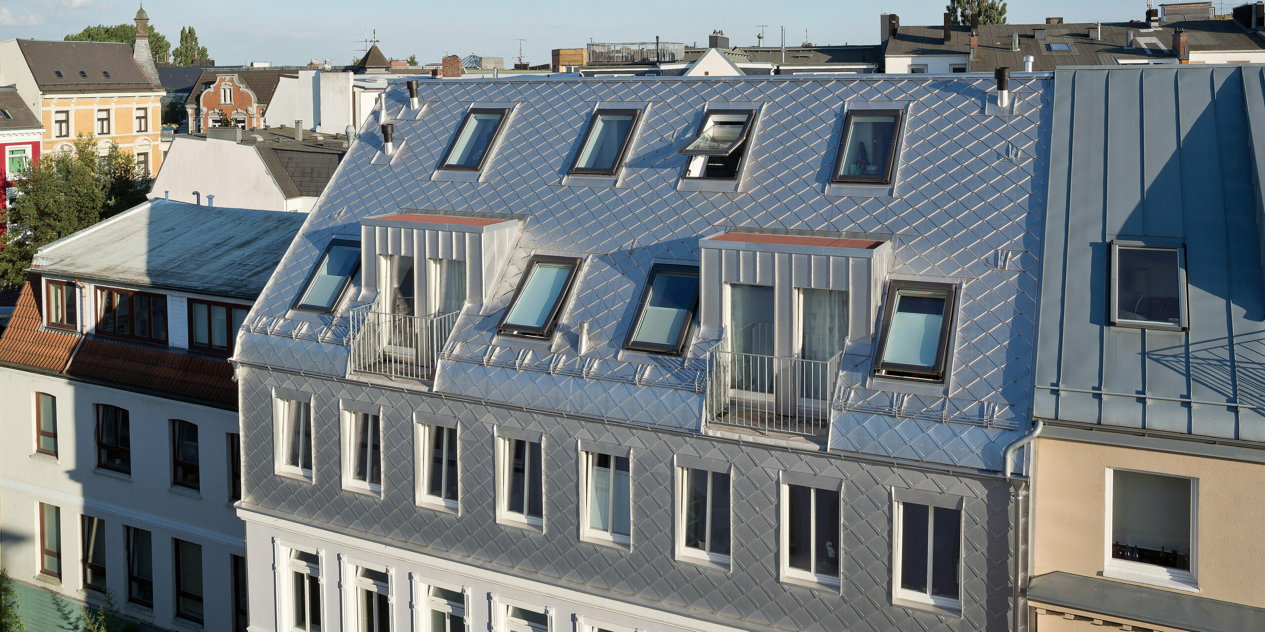 Das Dach dieses stilvollen Hauses in Hamburg erstrahlt mit der PREFA Dachraute 29 × 29 in edler Naturblank-Optik. Die präzise Verlegung der Rauten verleiht dem Gebäude einen markanten, modernen Look. Durch die Kombination aus traditionellen Fenstern und modernen Elementen fügt sich das Gebäude perfekt in die urbane Umgebung ein.