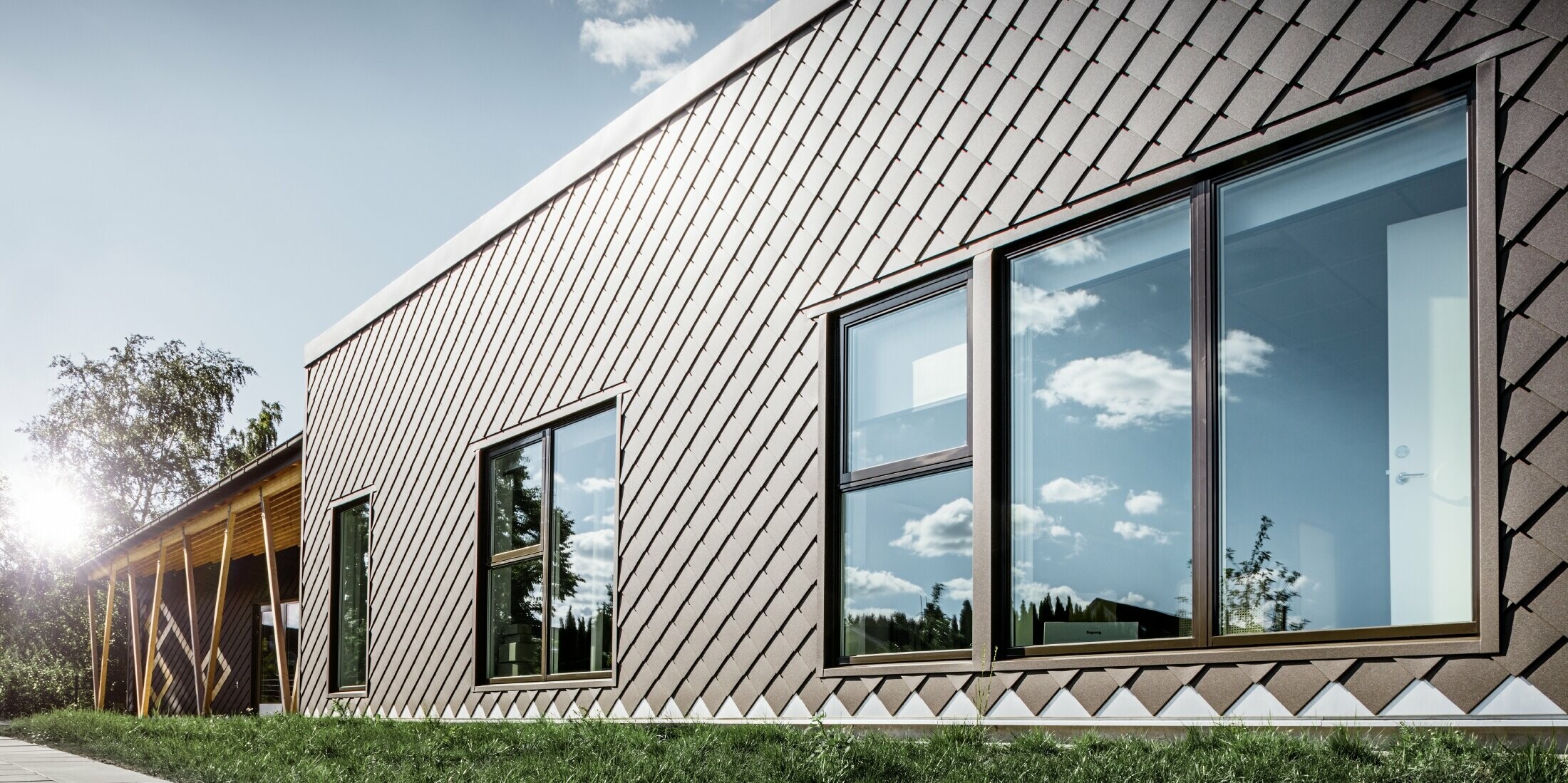 Diese Aufnahme der Vorschule in Stockholm zeigt die neue Fassade mit großen Fensterflächen und Flachdach. Die Außenfassade wurde mit der Fassadenraute 20x20 in Braun verkleidet.