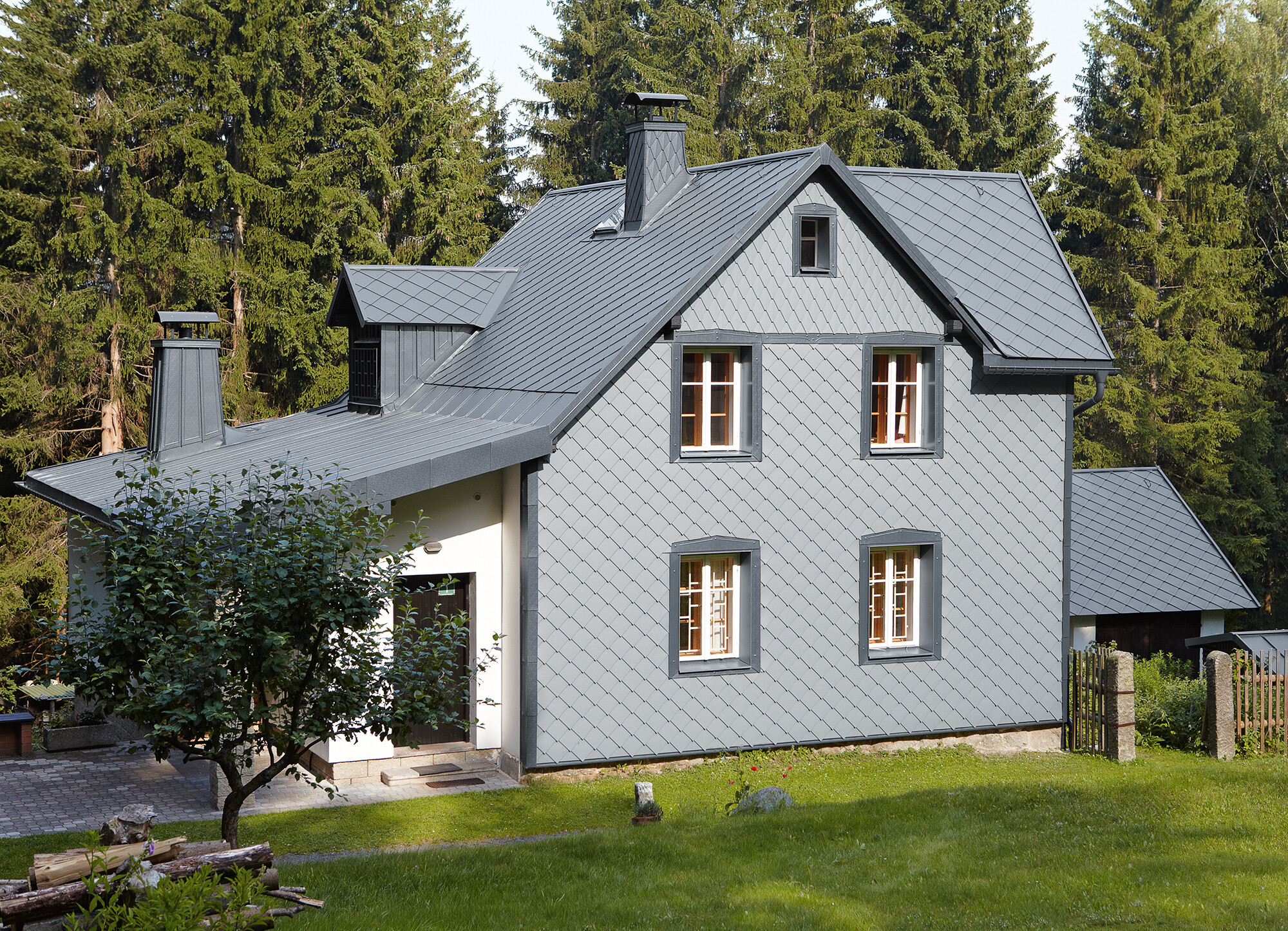 Maison individuelle dans un espace boisé avec façade en aluminium PREFA résistante aux intempéries en gris souris.