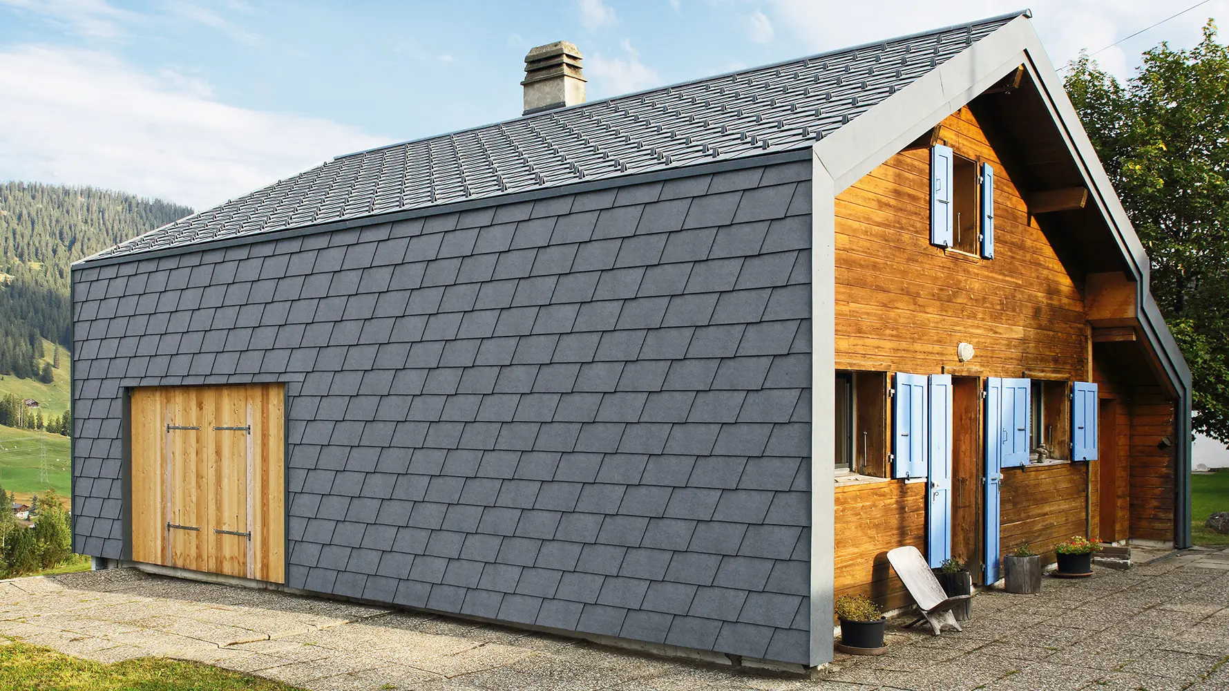 Maison individuelle moderne revêtue de bardeaux de façade PREFA couleur anthracite et d’éléments en bois.