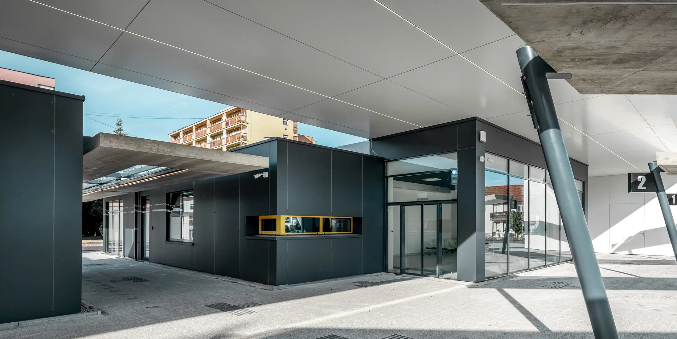 Überdachter Bereich des Busbahnhofs Lenti; Die Untersicht der Überdachung ist mit PREFABOND Verbundplatte in Reinweiß verkleidet, die Fassadenelemente beim Eingangsbereich in P.10 Anthrazit.