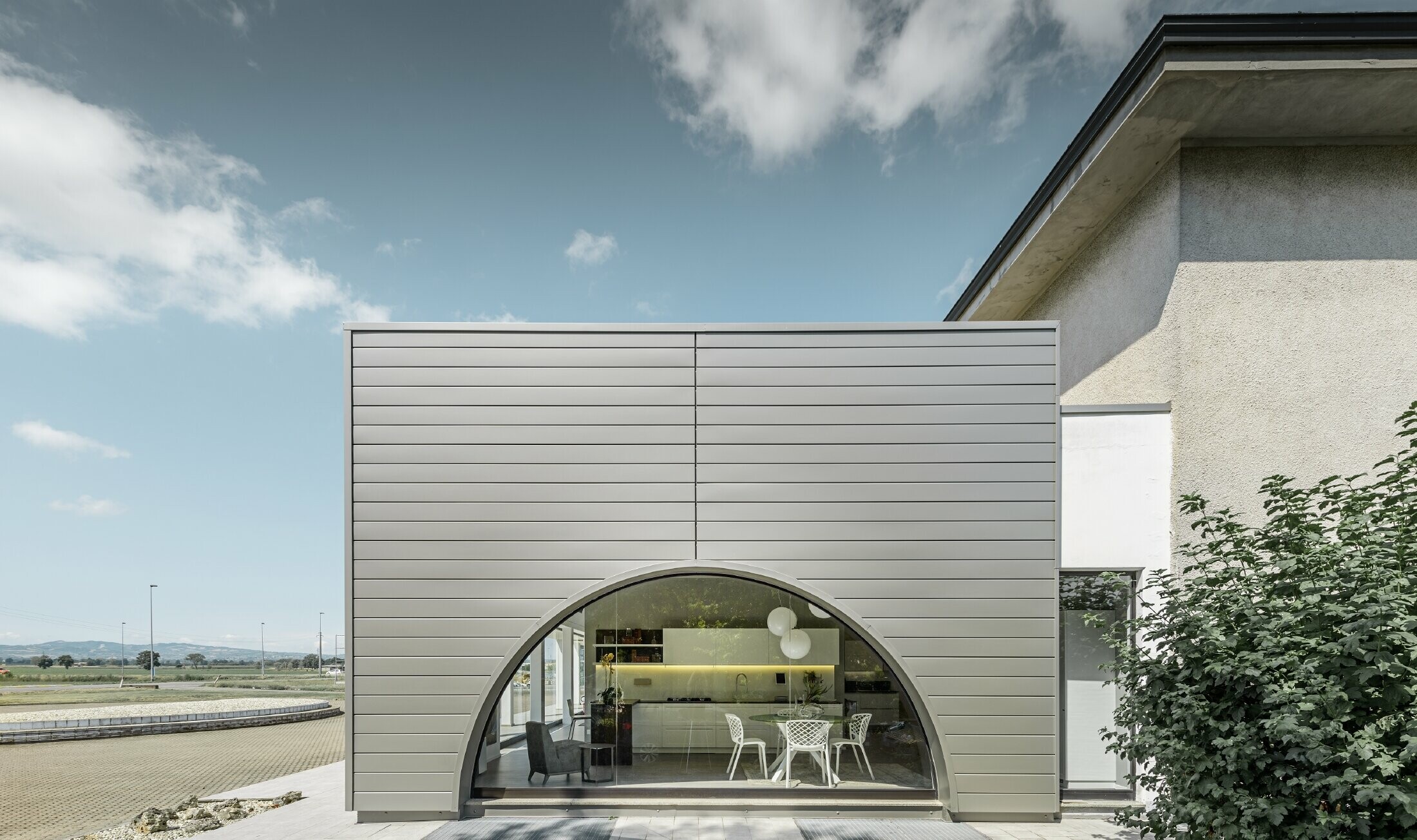 Geradlinige Fassade mit gebogenem Schaufenster; Fassadenverkleidung aus Aluminium vom PREFA mit den Sidings in Rauchsilber