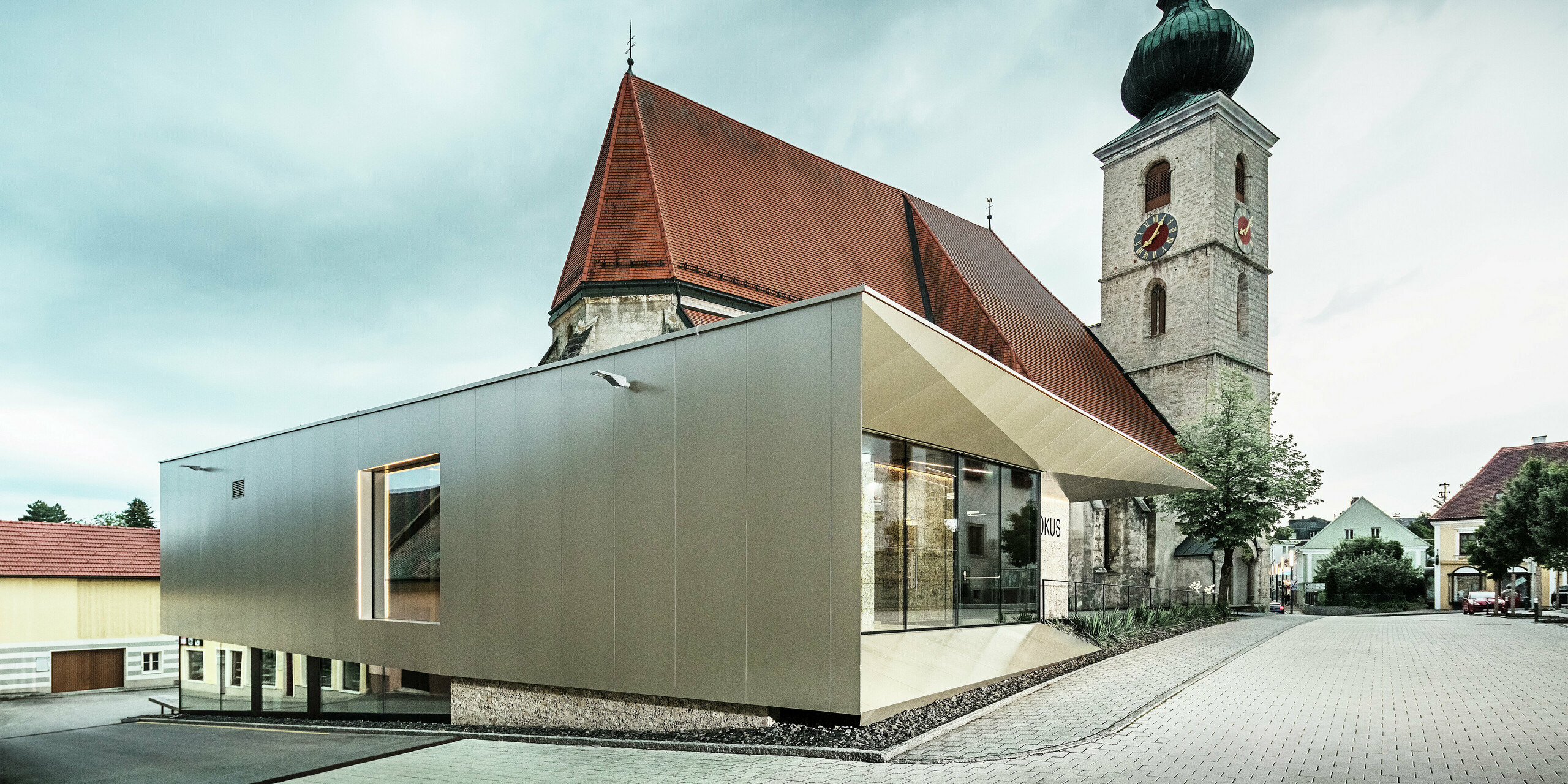 Die seitliche Ansicht zeigt den filigranen Dachüberstand, realisiert mit hochwertigen PREFA Aluminium Verbundplatten. Die exakte Verarbeitung ermöglicht eine moderne Optik mit klaren Linien und unterstreicht die architektonische Verbindung zwischen Alt und Neu.