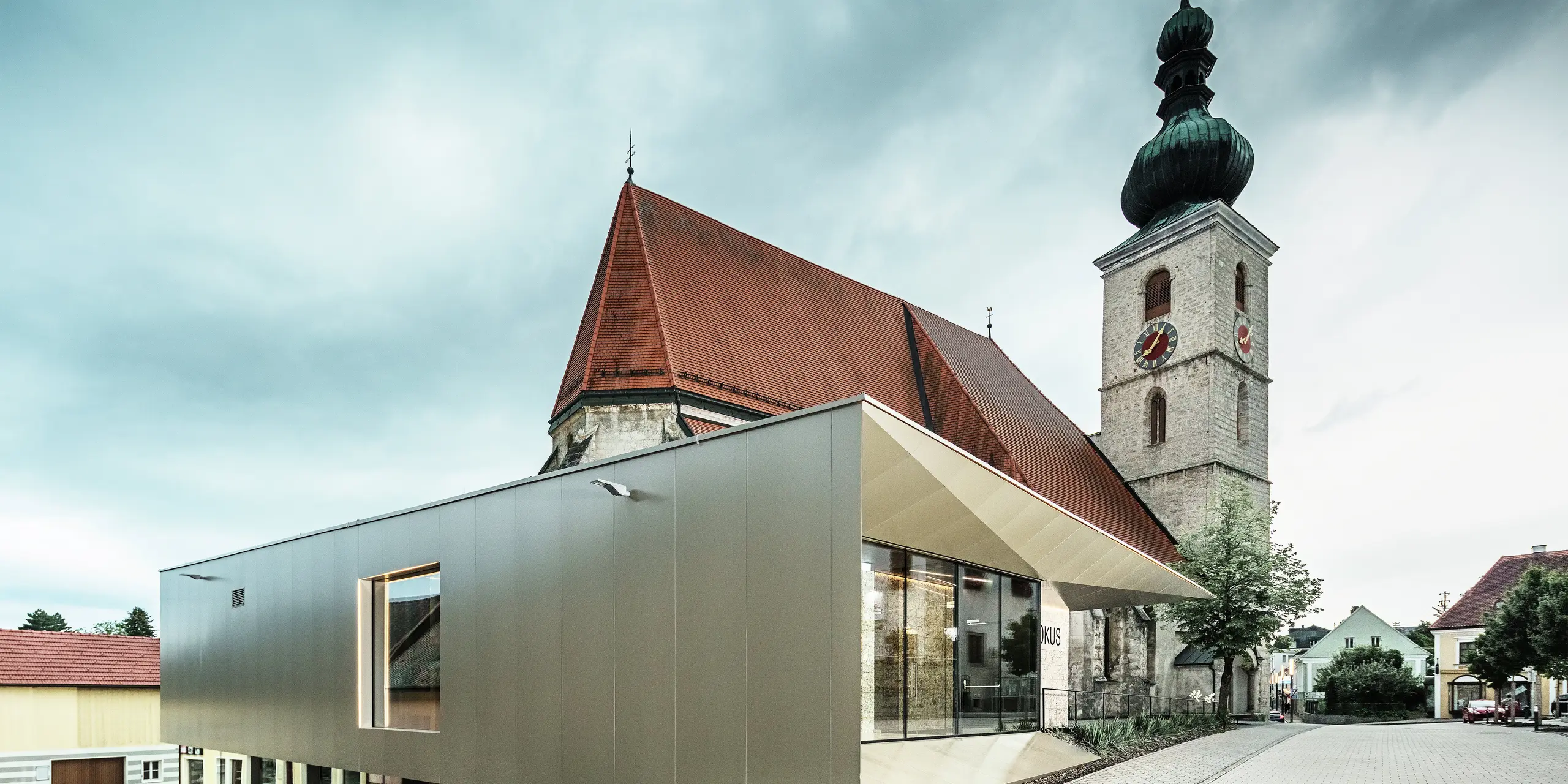 Het zijaanzicht toont de filigrane dakoverstek, gerealiseerd met hoogwaardige PREFA aluminium composietplaten. De nauwkeurige afwerking zorgt voor een moderne uitstraling met strakke lijnen en benadrukt de architectonische verbinding tussen oud en nieuw.