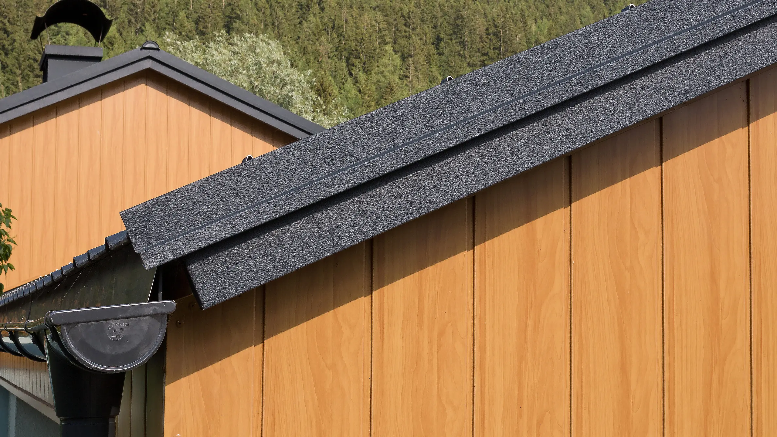 Topgevel bekleed met verticaal gemonteerde aluminium sidings van PREFA in eiken naturel, met PREFA dakgoot in antraciet.